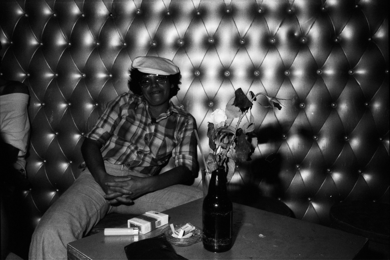 A man sitting on a couch next to a vase of flowers.