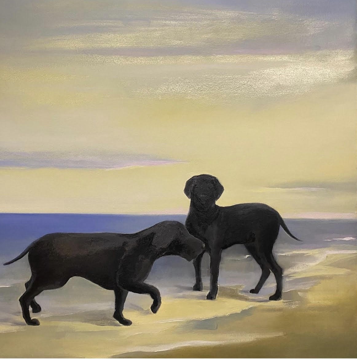 Two black dogs stand on a beach under a soft, pastel sky.