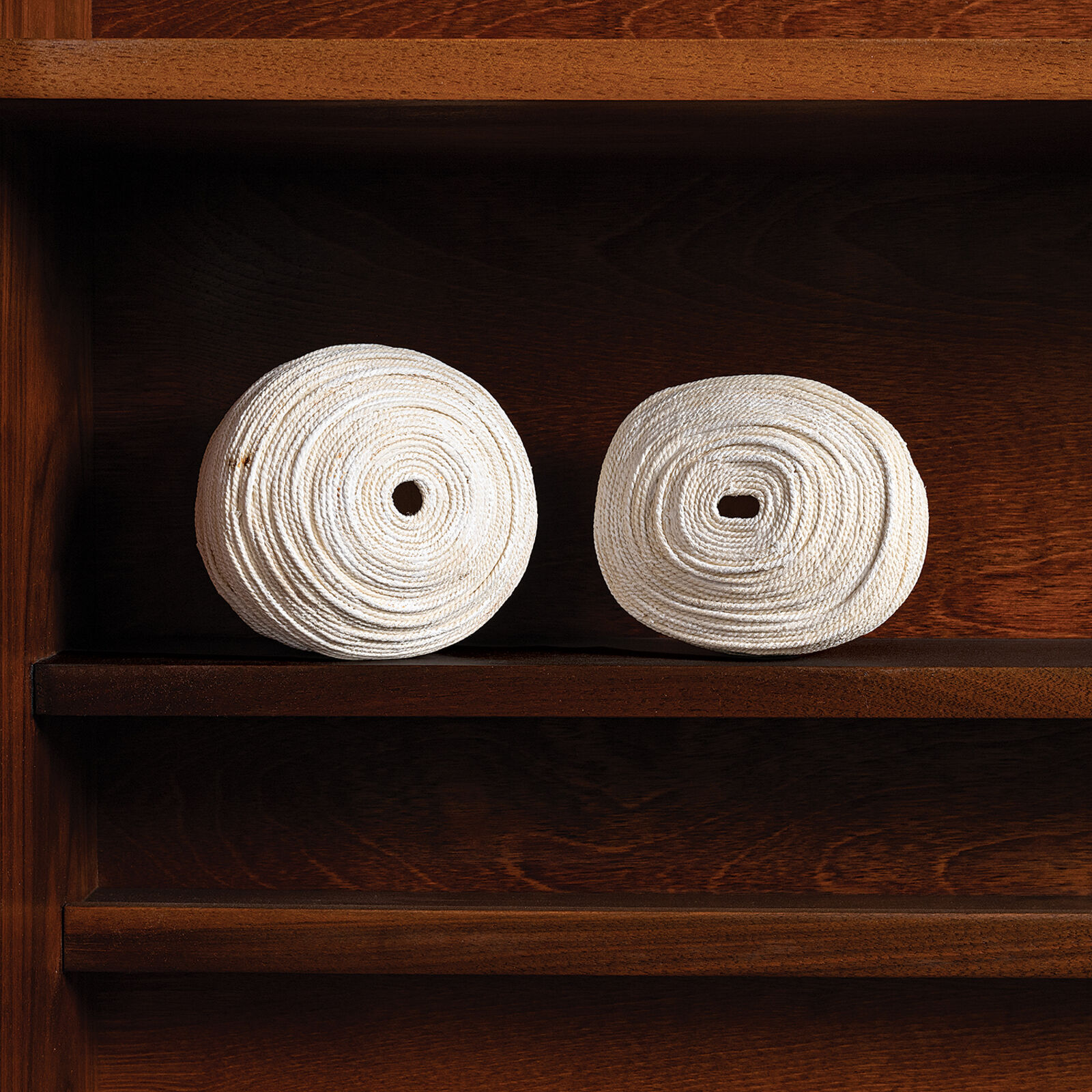 Two rolls of toilet paper sitting on top of a wooden shelf.