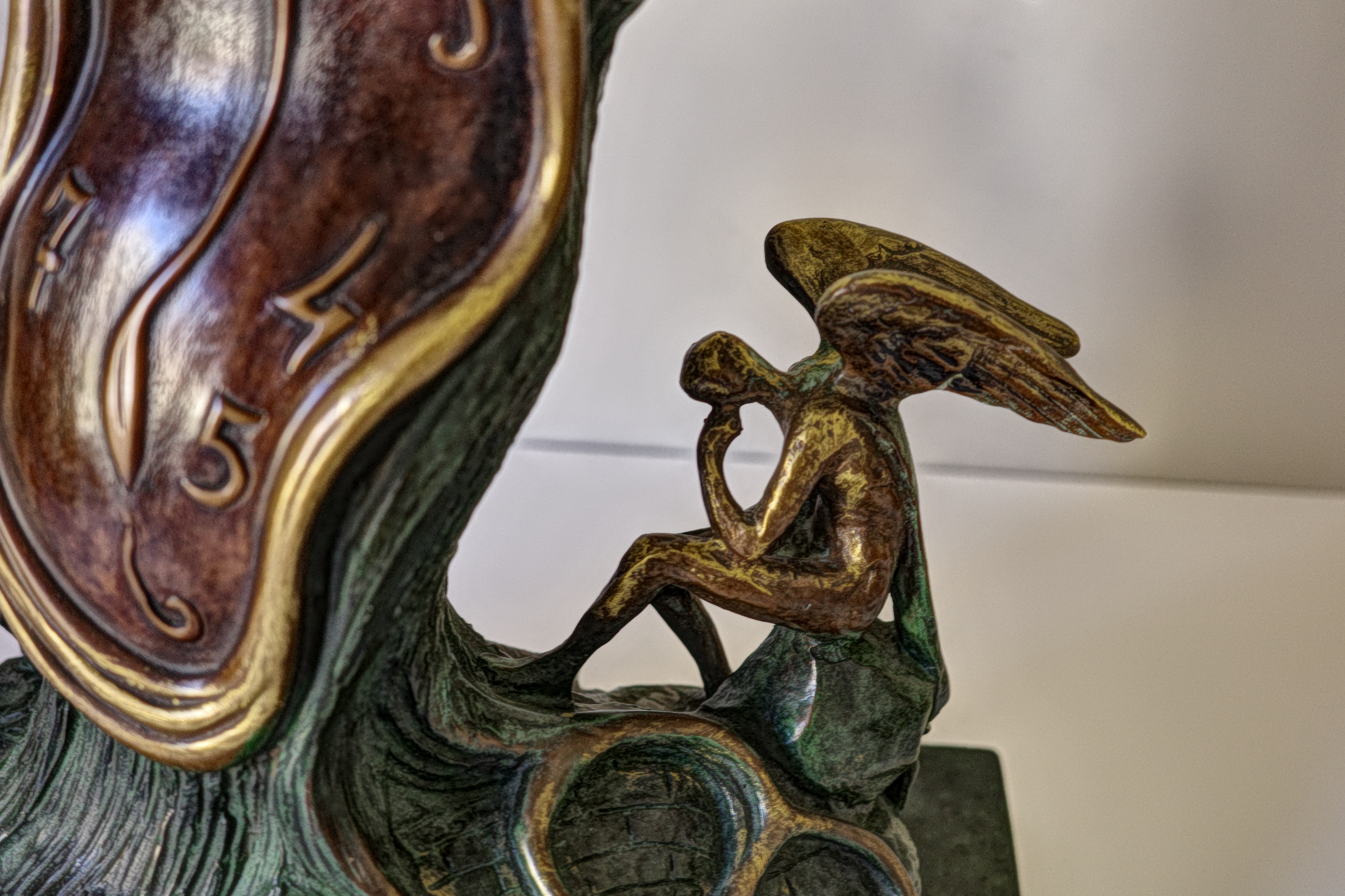 A bronze sculpture of a clock on top of a tree.