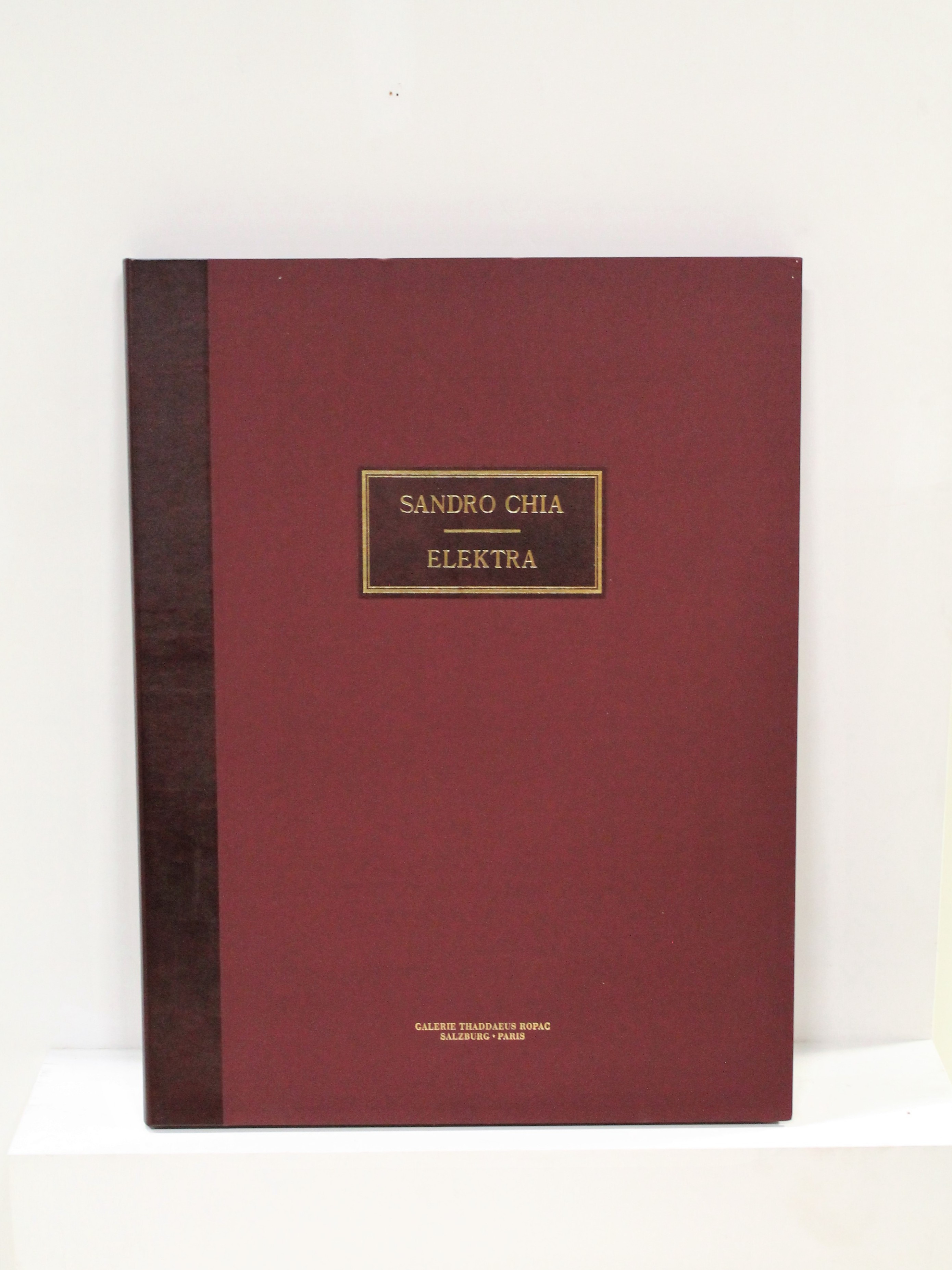 A red book sitting on top of a white shelf.