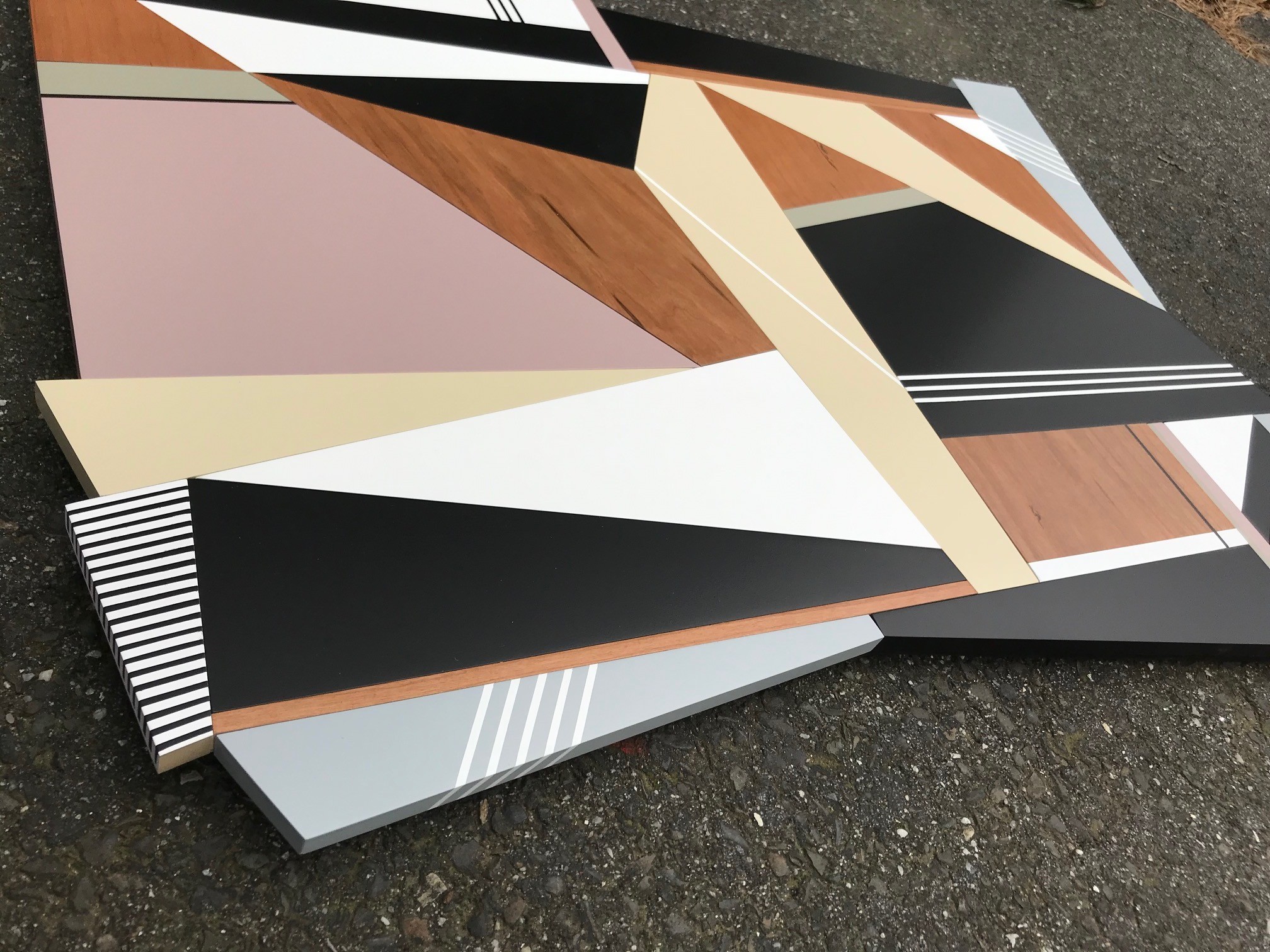A geometric abstract composition featuring layered wooden and painted panels in a dynamic, fragmented arrangement.
