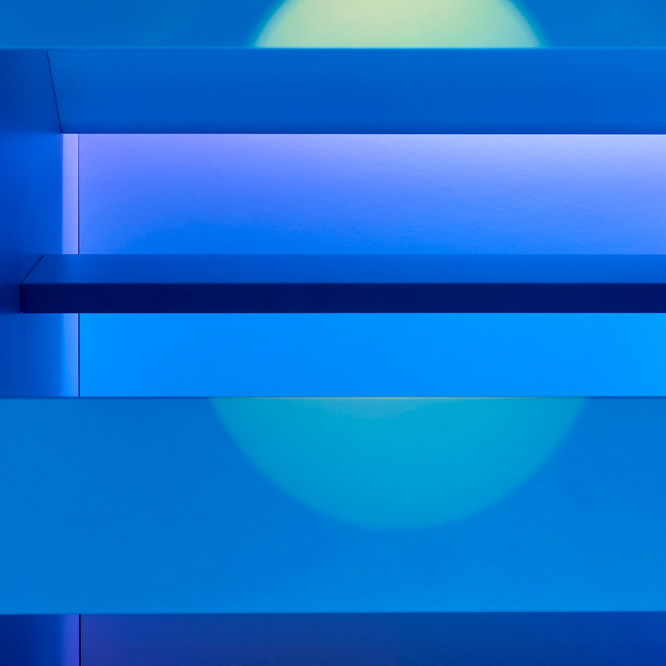 A blue wall with shelves and a blue light on it.