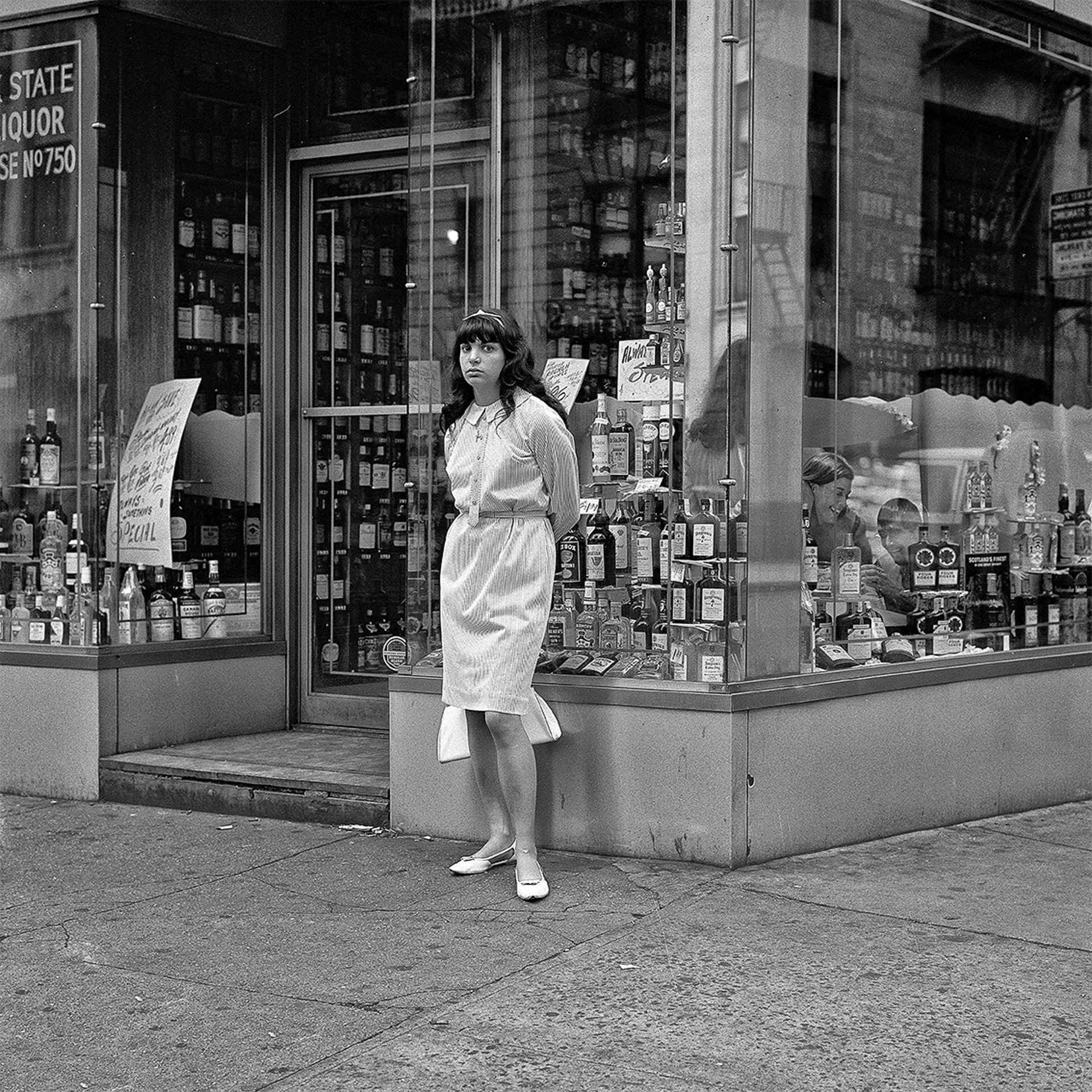 A woman standing in front of a liquor store.