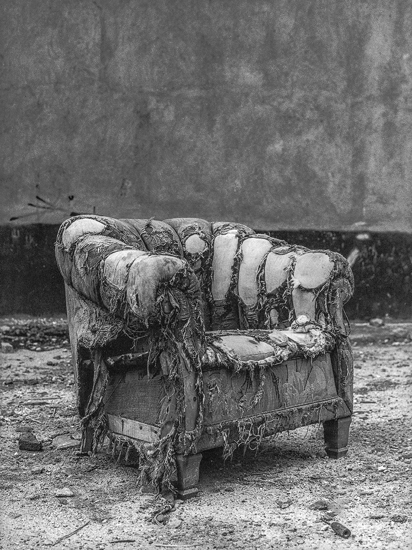 A chair that is sitting in the dirt. 