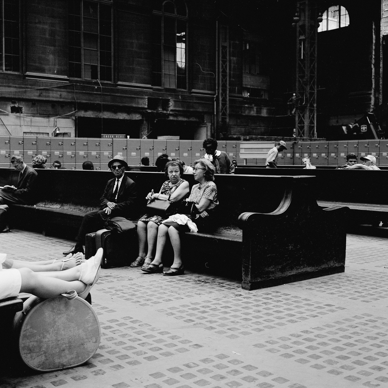 A group of people sitting on a bench in a train station.