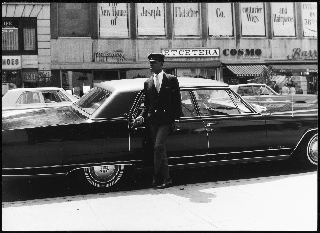 A man in a suit and tie standing next to a black car.