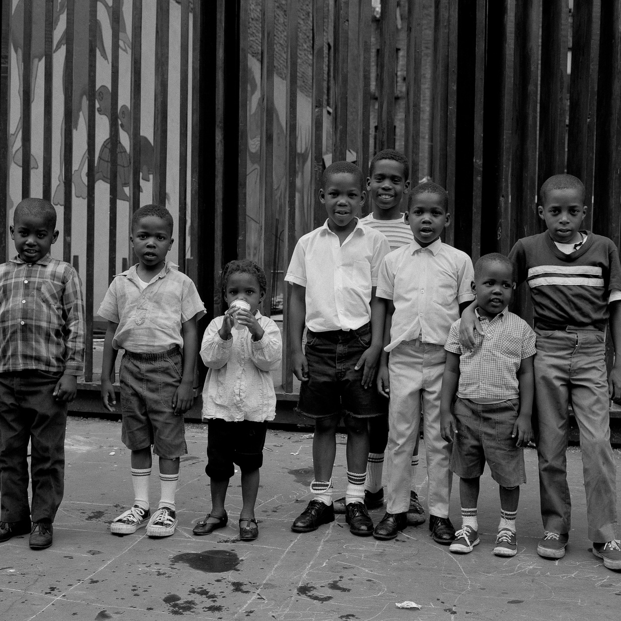 A group of children standing next to each other in front of a fence.