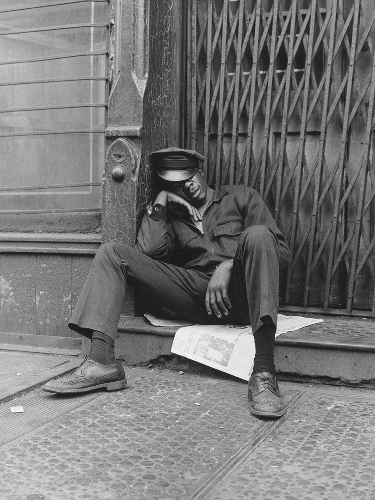 A man sitting on the sidewalk with his head in his hands.