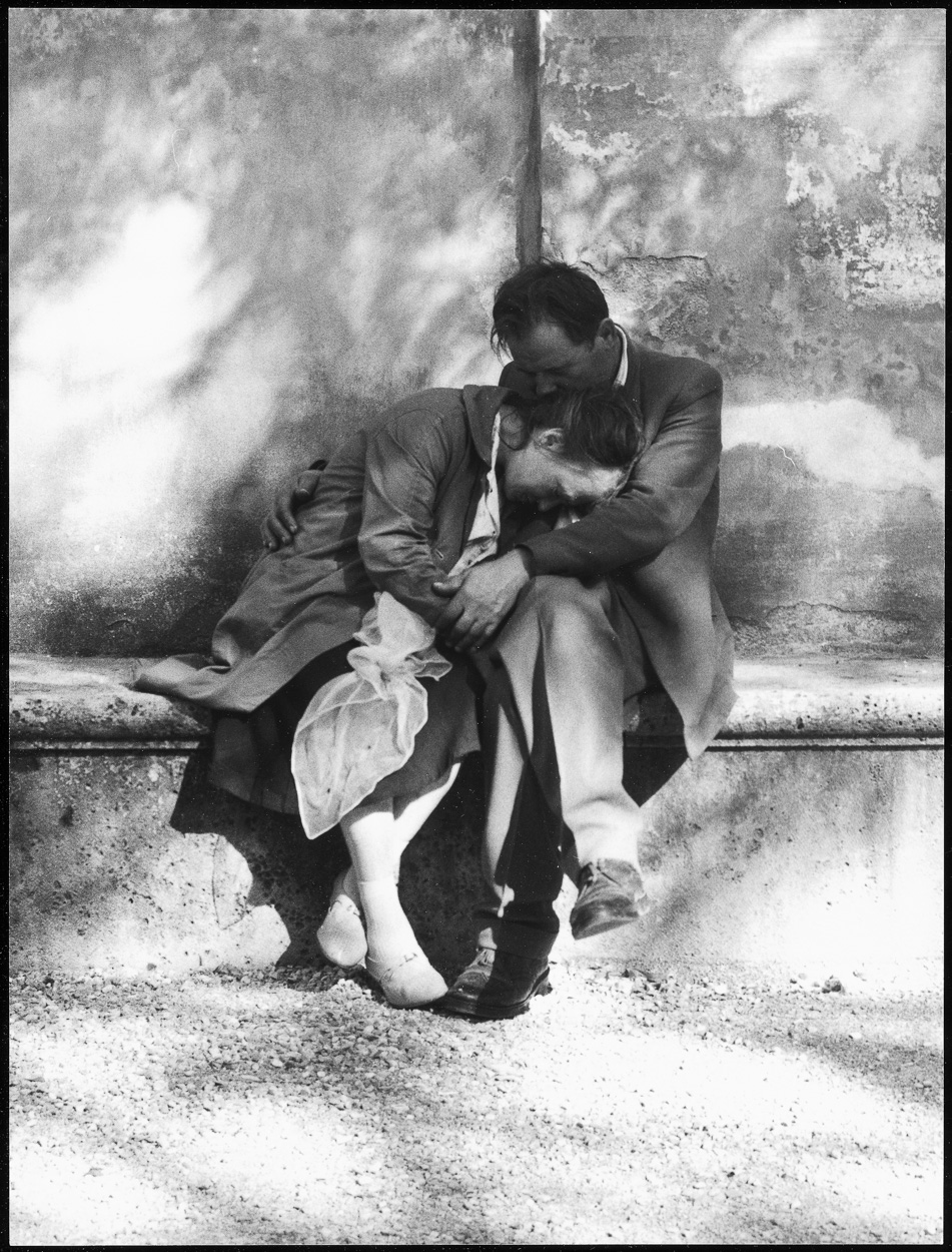 A man and a woman sitting on a stone wall.