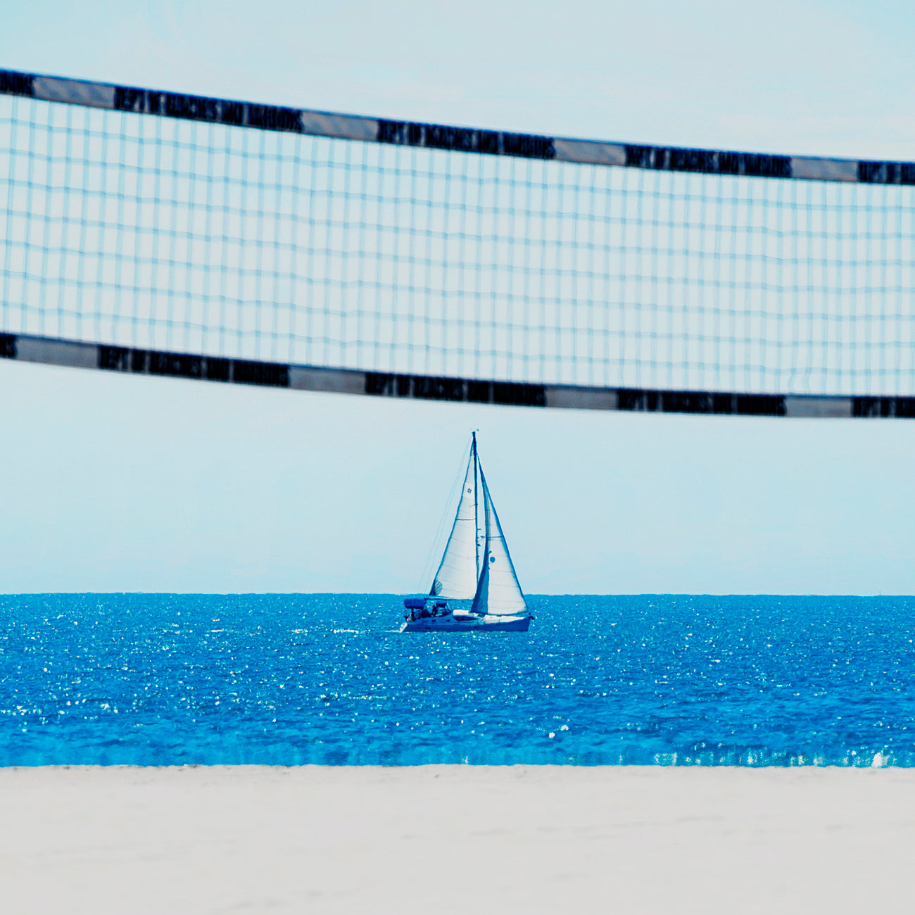 A picture of a beach scene with a sailboat in the distance.