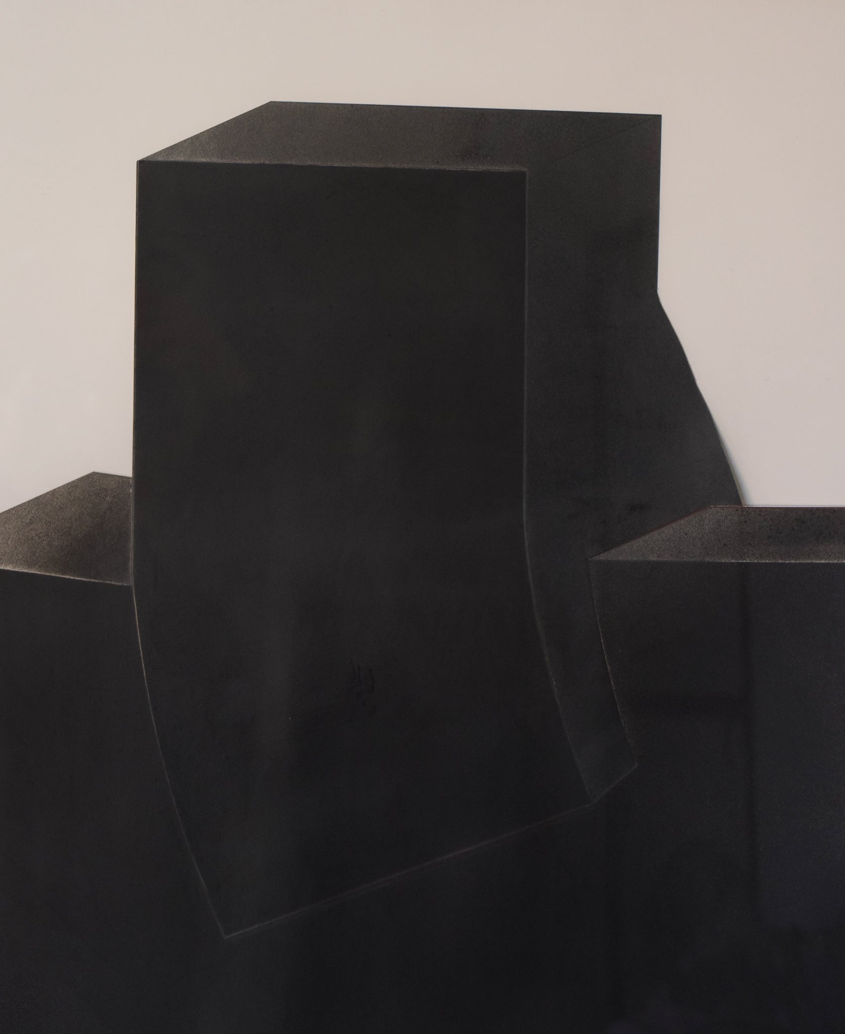A black sculpture on a white wall in a room.