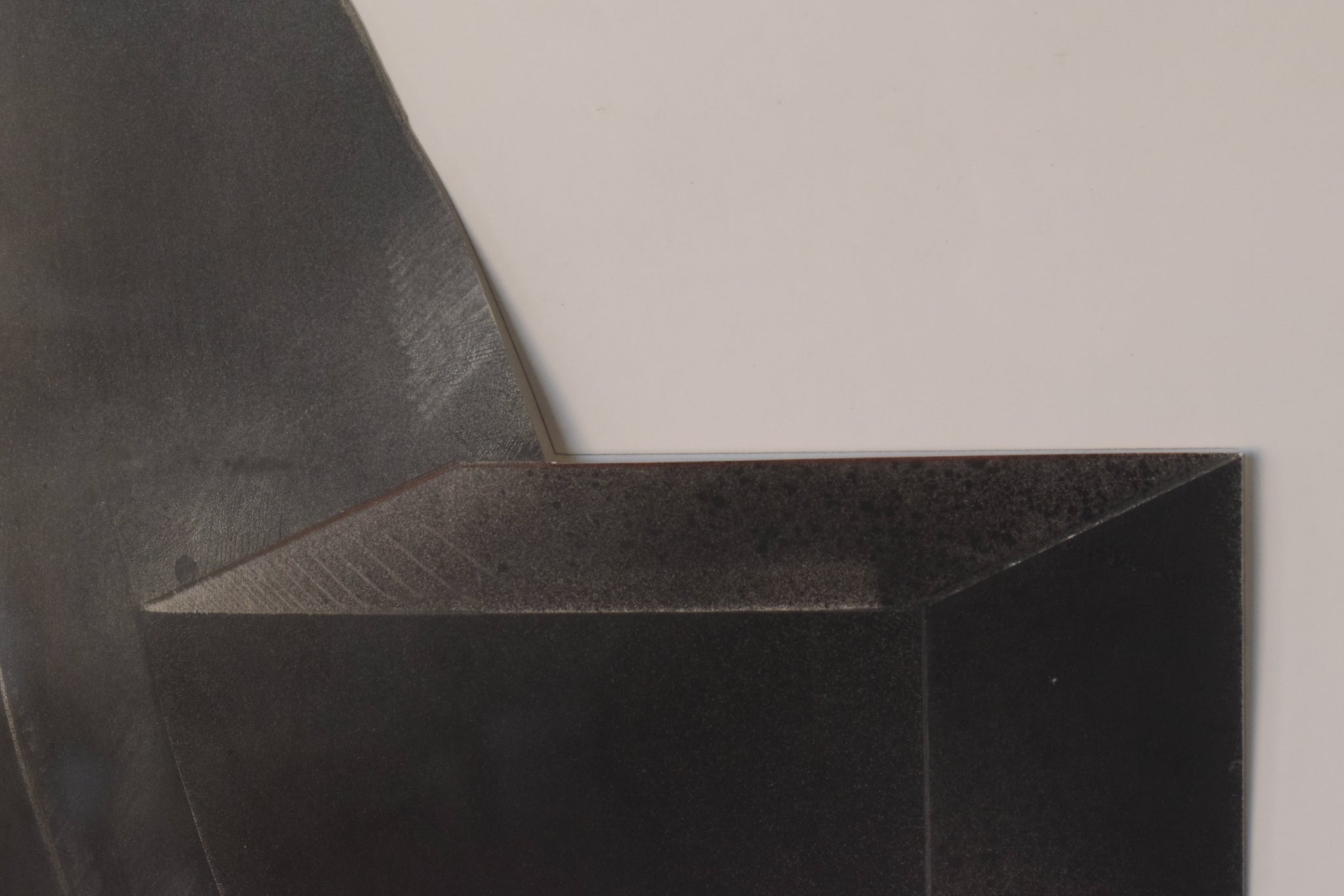 A black sculpture on a white wall in a room.