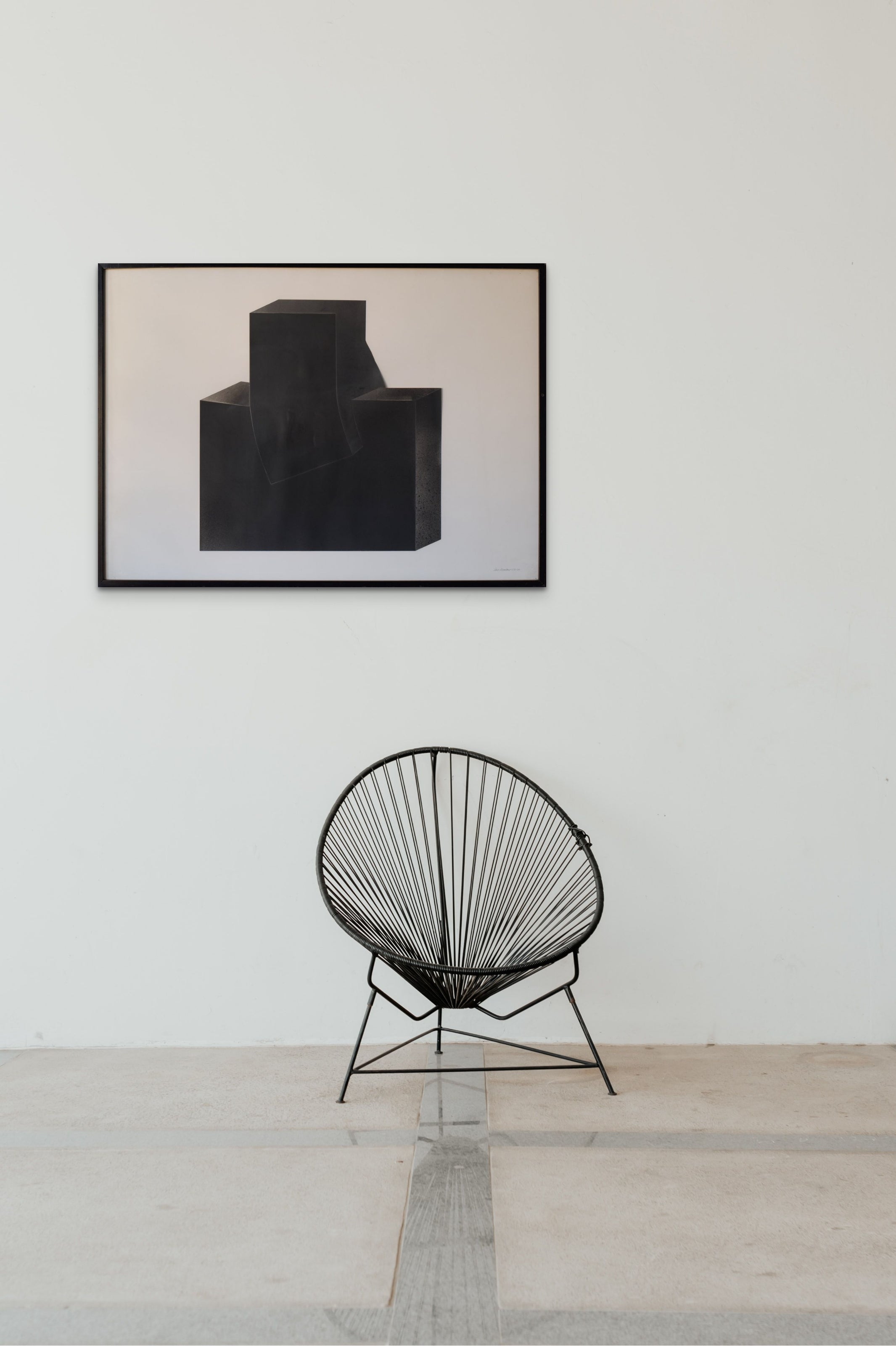 A black sculpture on a white wall in a room.