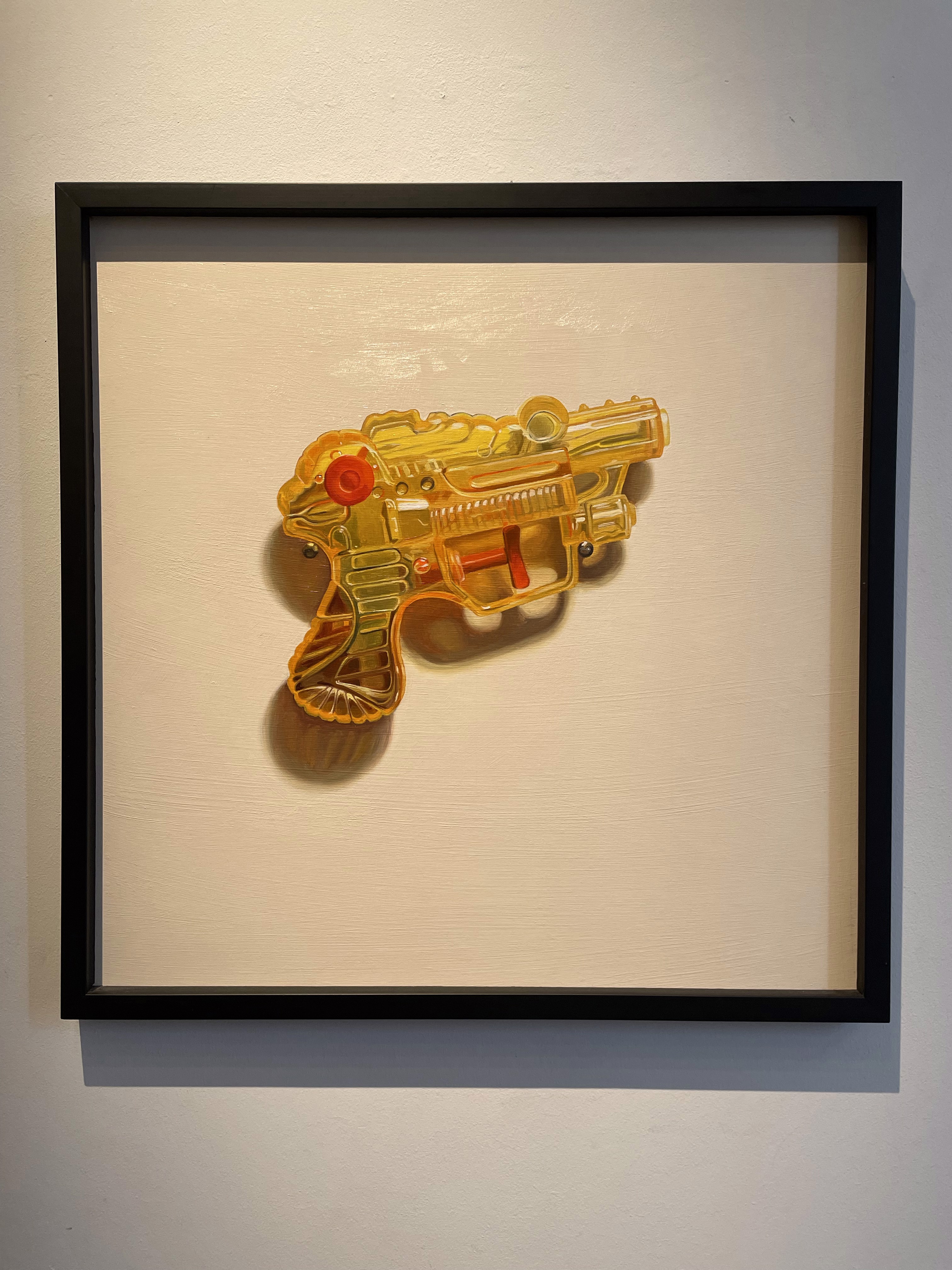 A picture of a yellow toy gun hanging on a wall.
