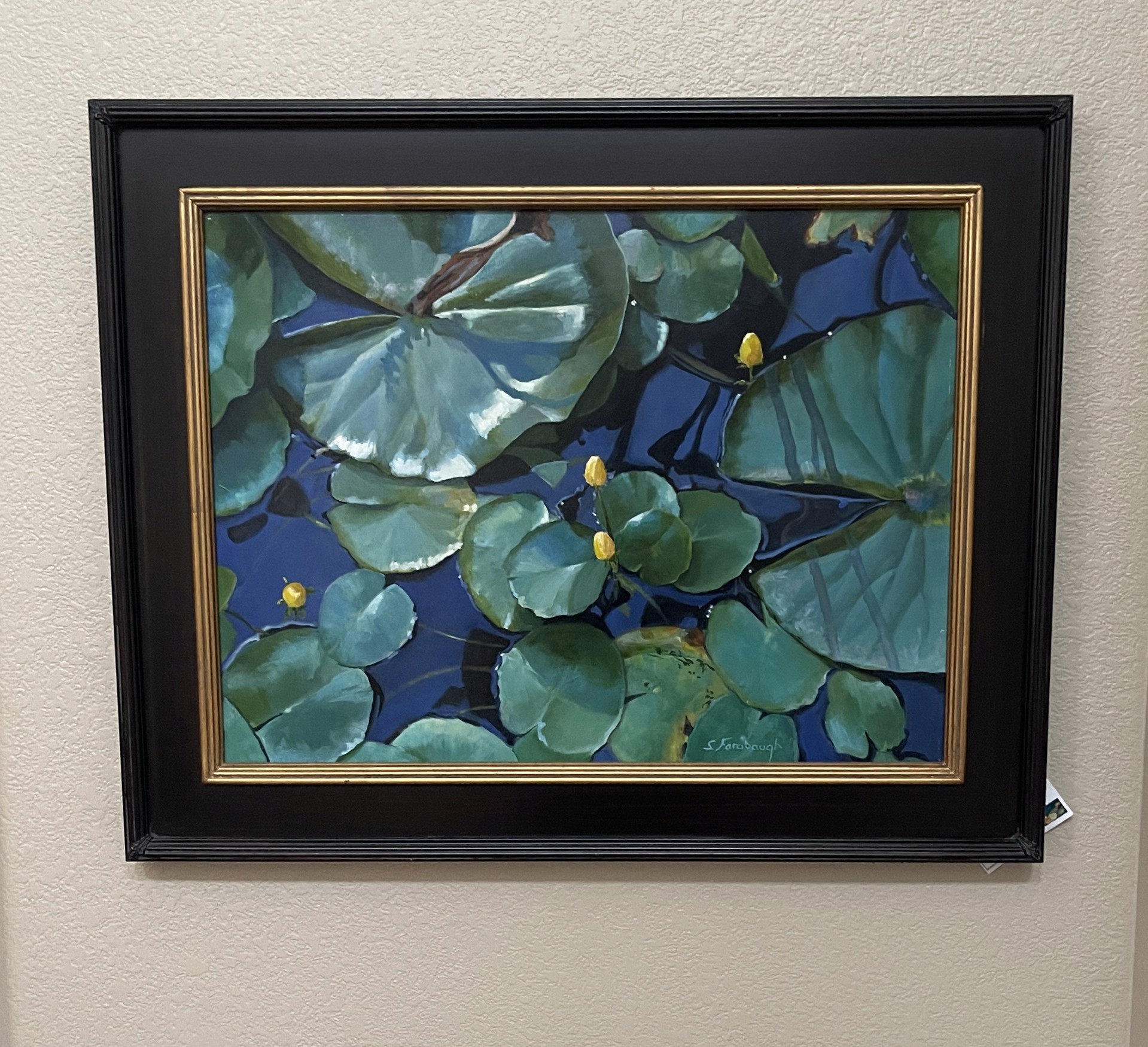 A painting of water lilies in a pond with blue water.