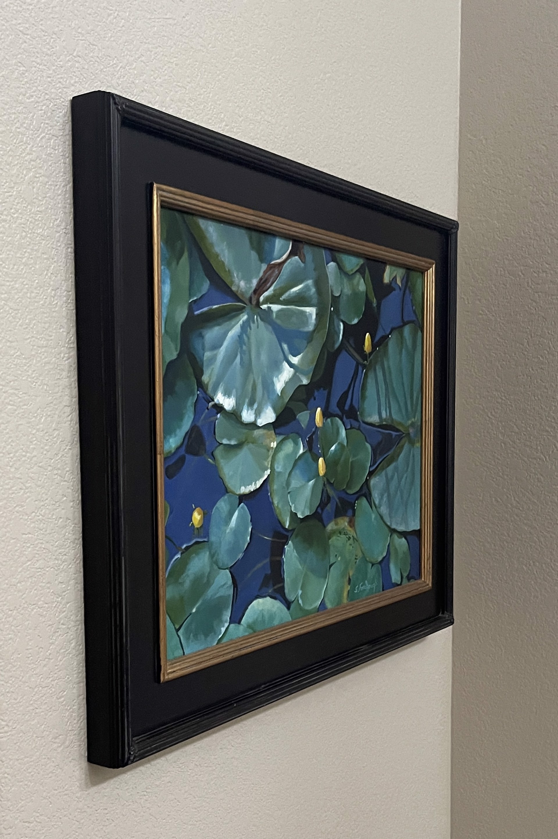 A painting of water lilies in a pond with blue water.