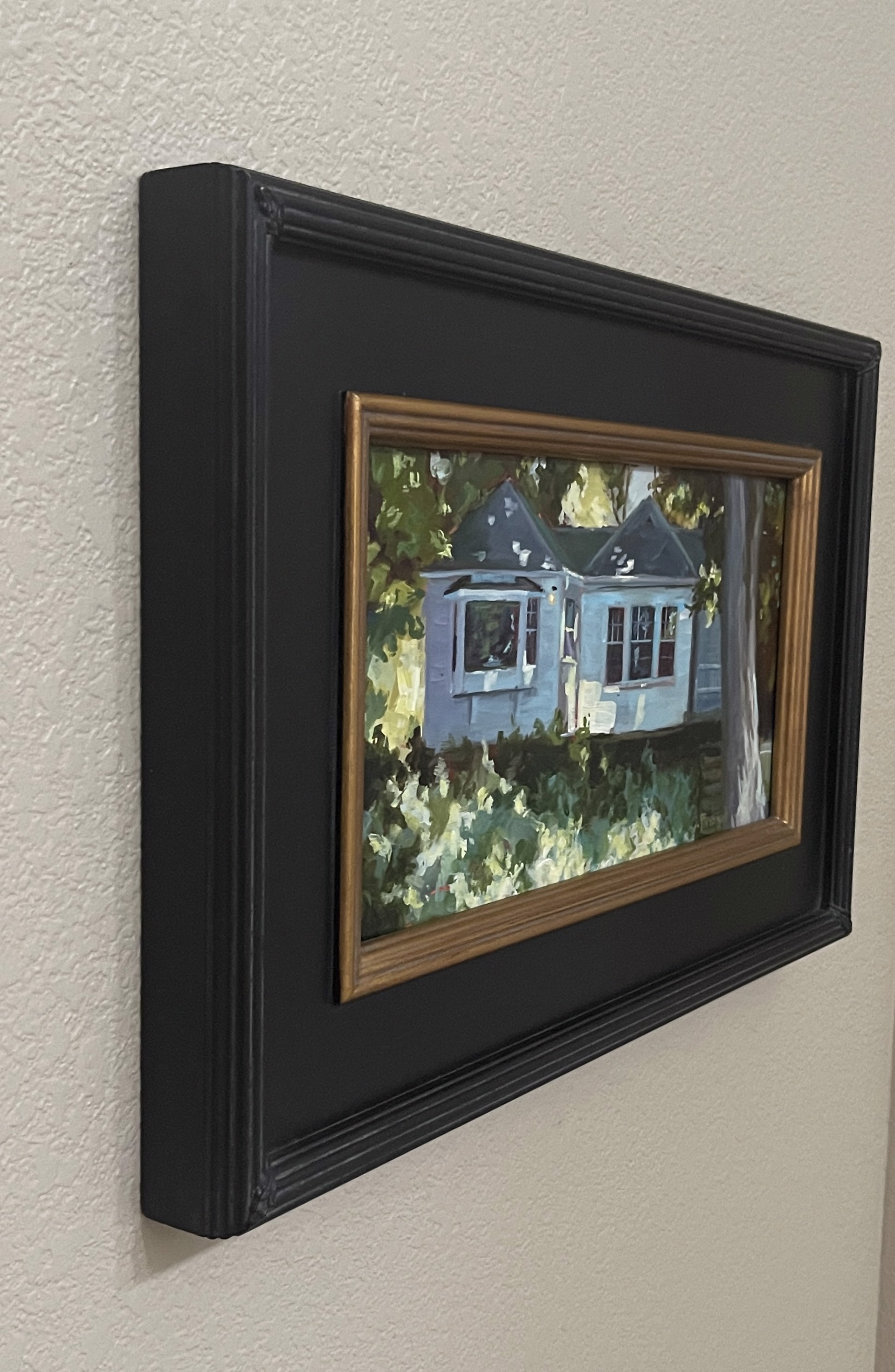 A painting of a blue house in the woods.