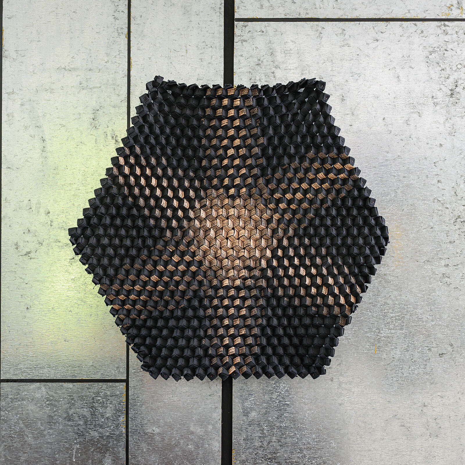 A black and copper sculpture on a white wall.