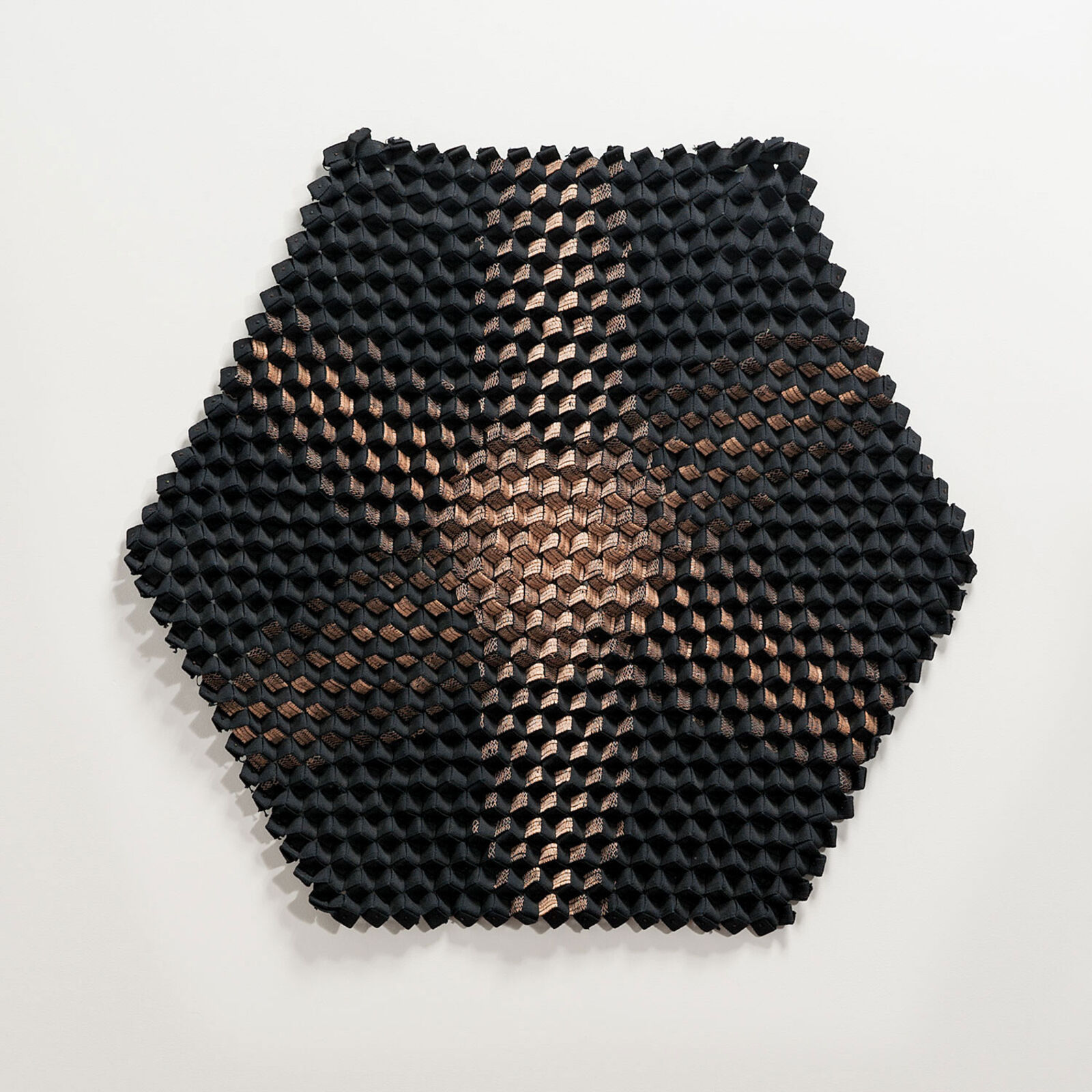A black and copper sculpture on a white wall.