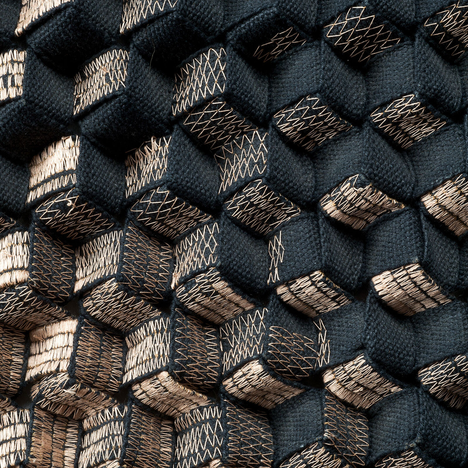 A black and copper sculpture on a white wall.