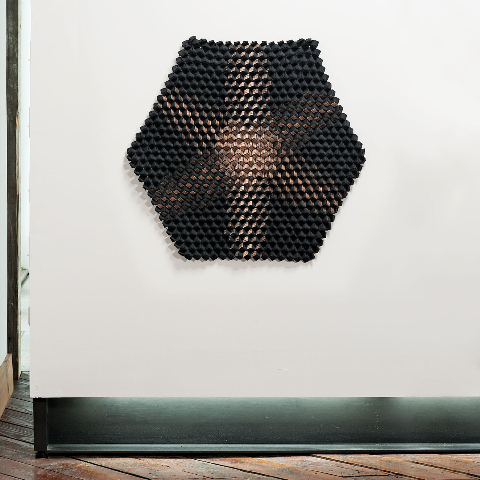 A black and copper sculpture on a white wall.