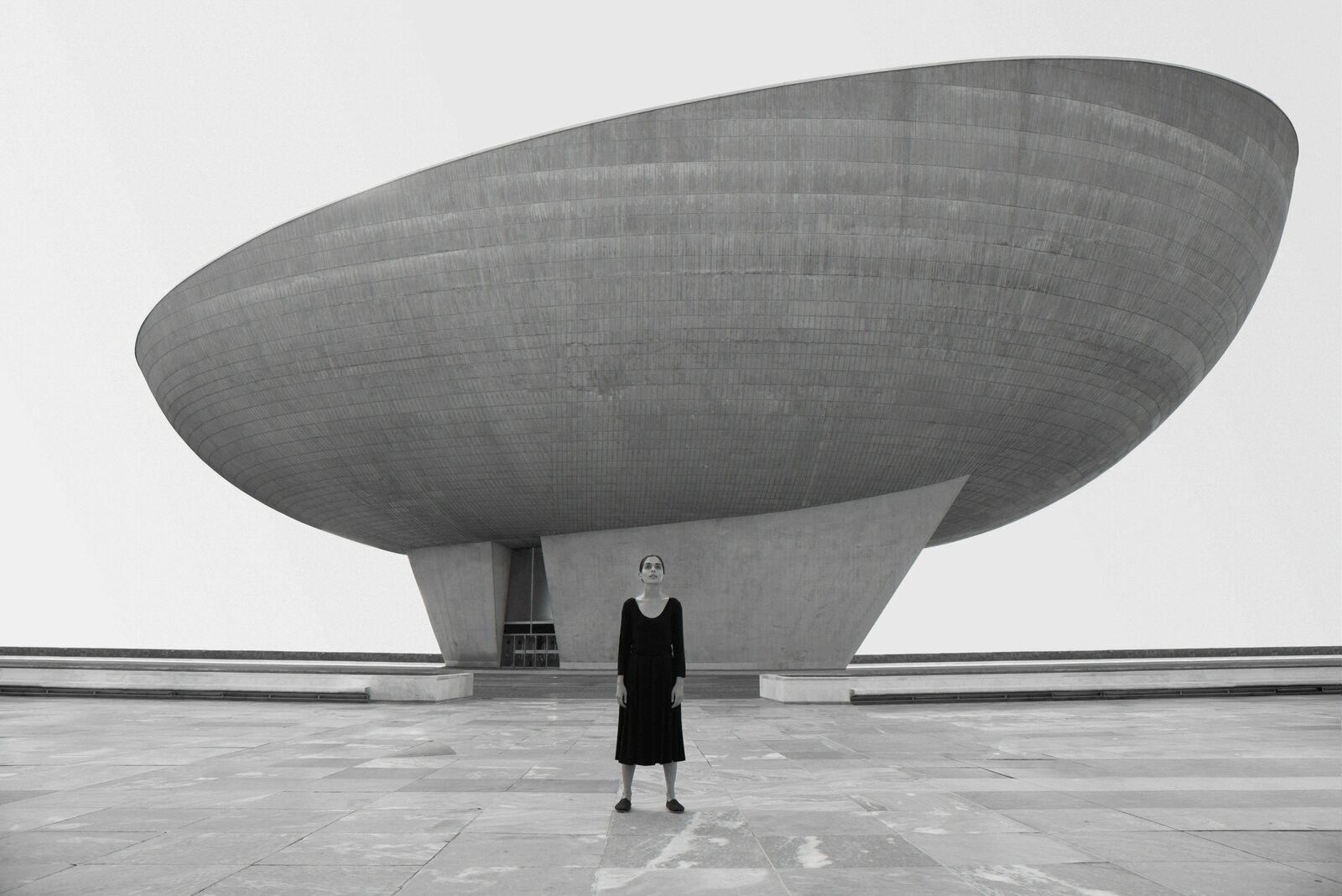 A woman standing in front of a large building.