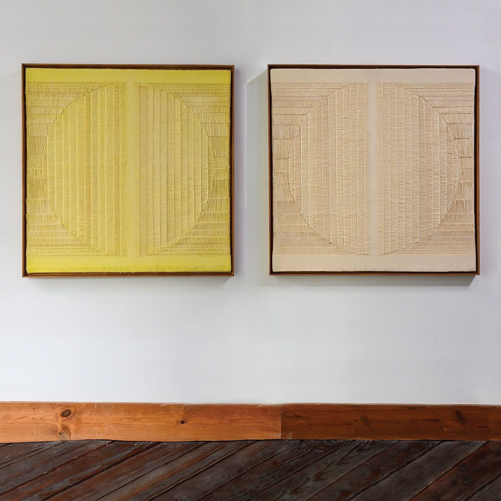 A minimalist textile artwork featuring a yellow stitched circle on a textured background.
