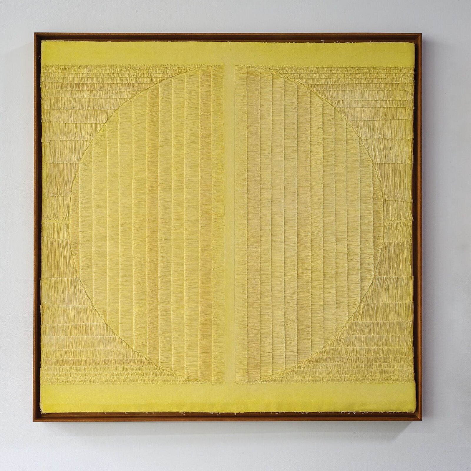 A minimalist textile artwork featuring a yellow stitched circle on a textured background.