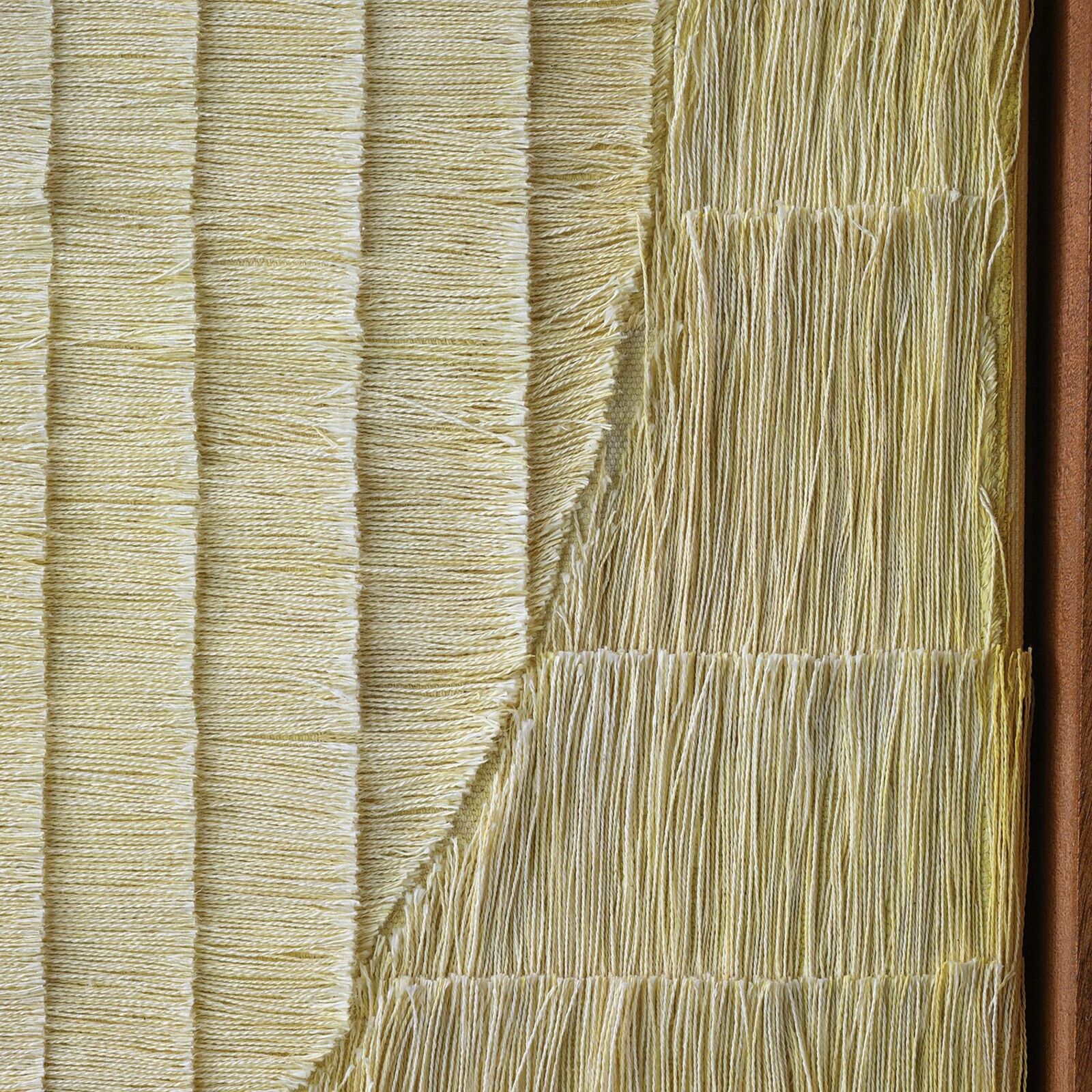 A minimalist textile artwork featuring a yellow stitched circle on a textured background.