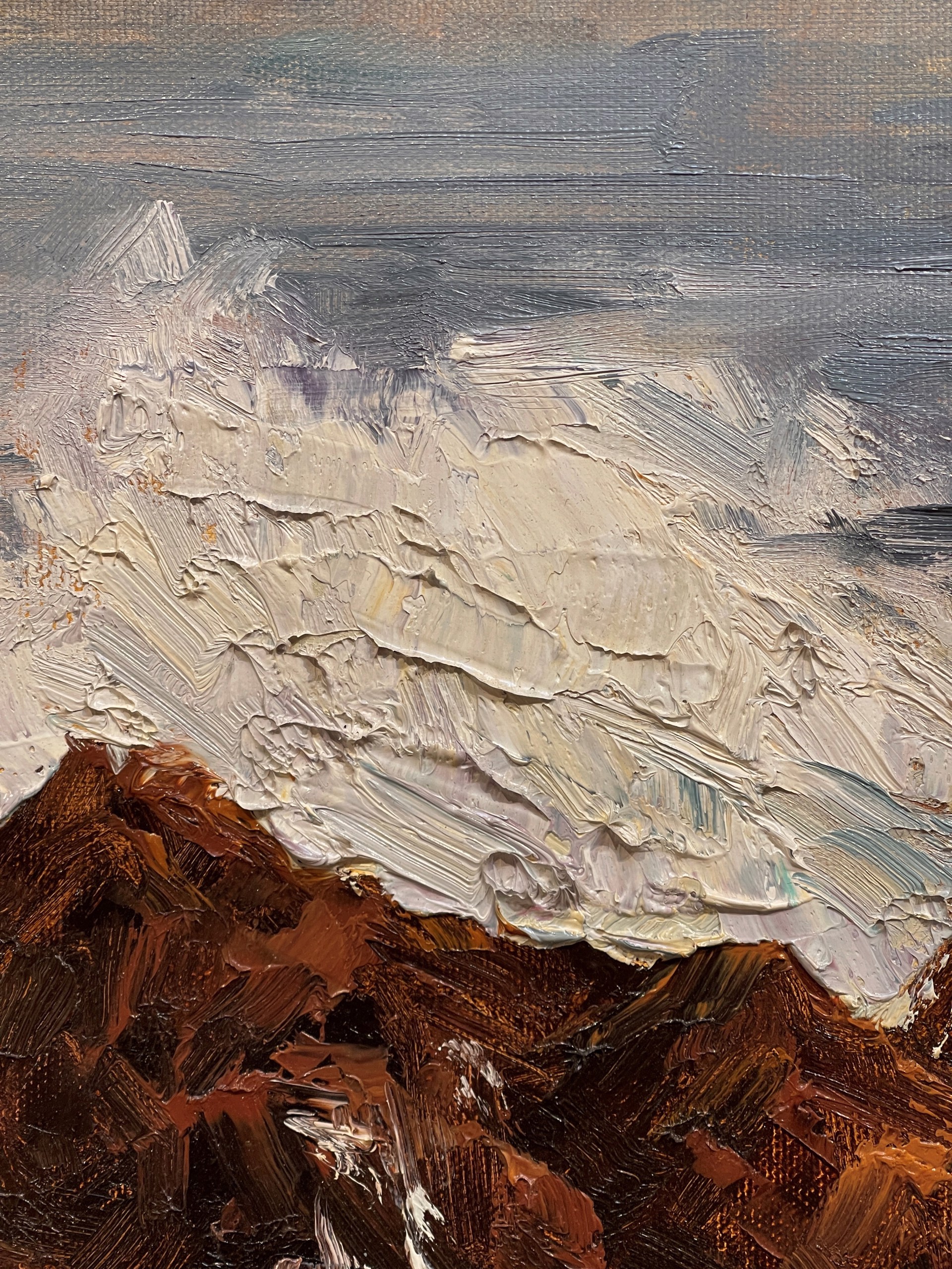 A painting of a rocky shoreline with waves crashing on the rocks.