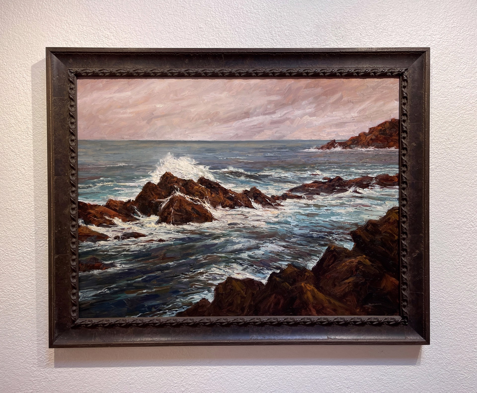 A painting of a rocky shoreline with waves crashing on the rocks.