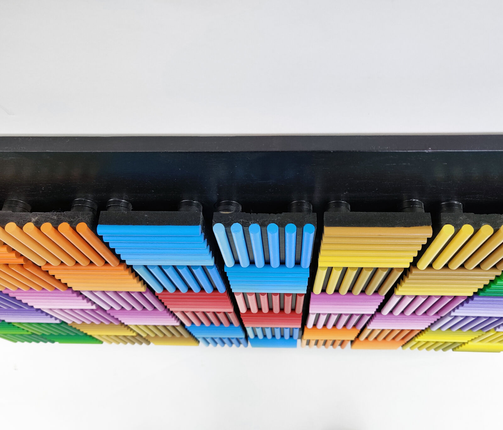 A painting of a colorful pattern of colored pencils on a black background.