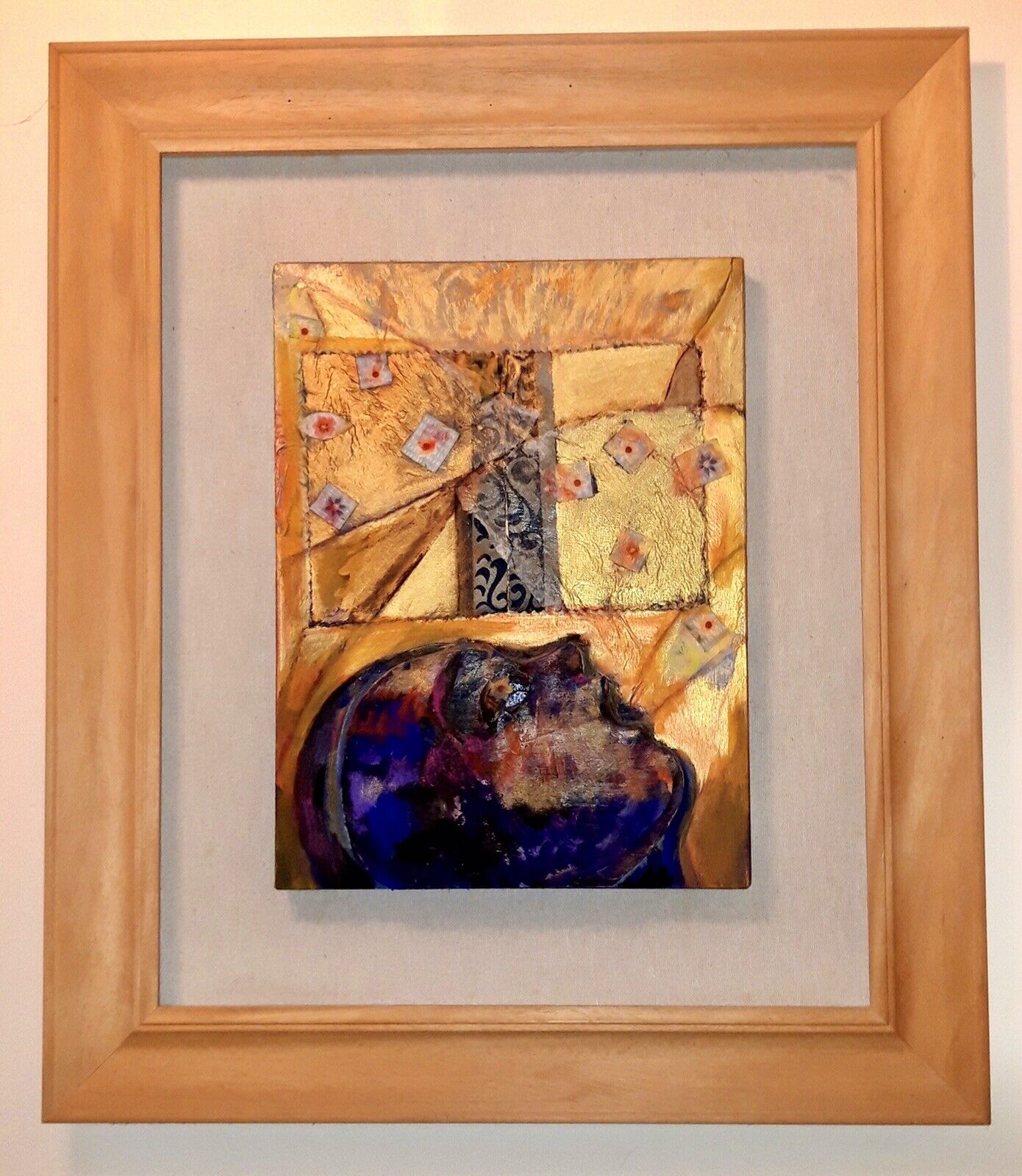 A framed artwork featuring a dark profile against a textured golden background with scattered small squares.