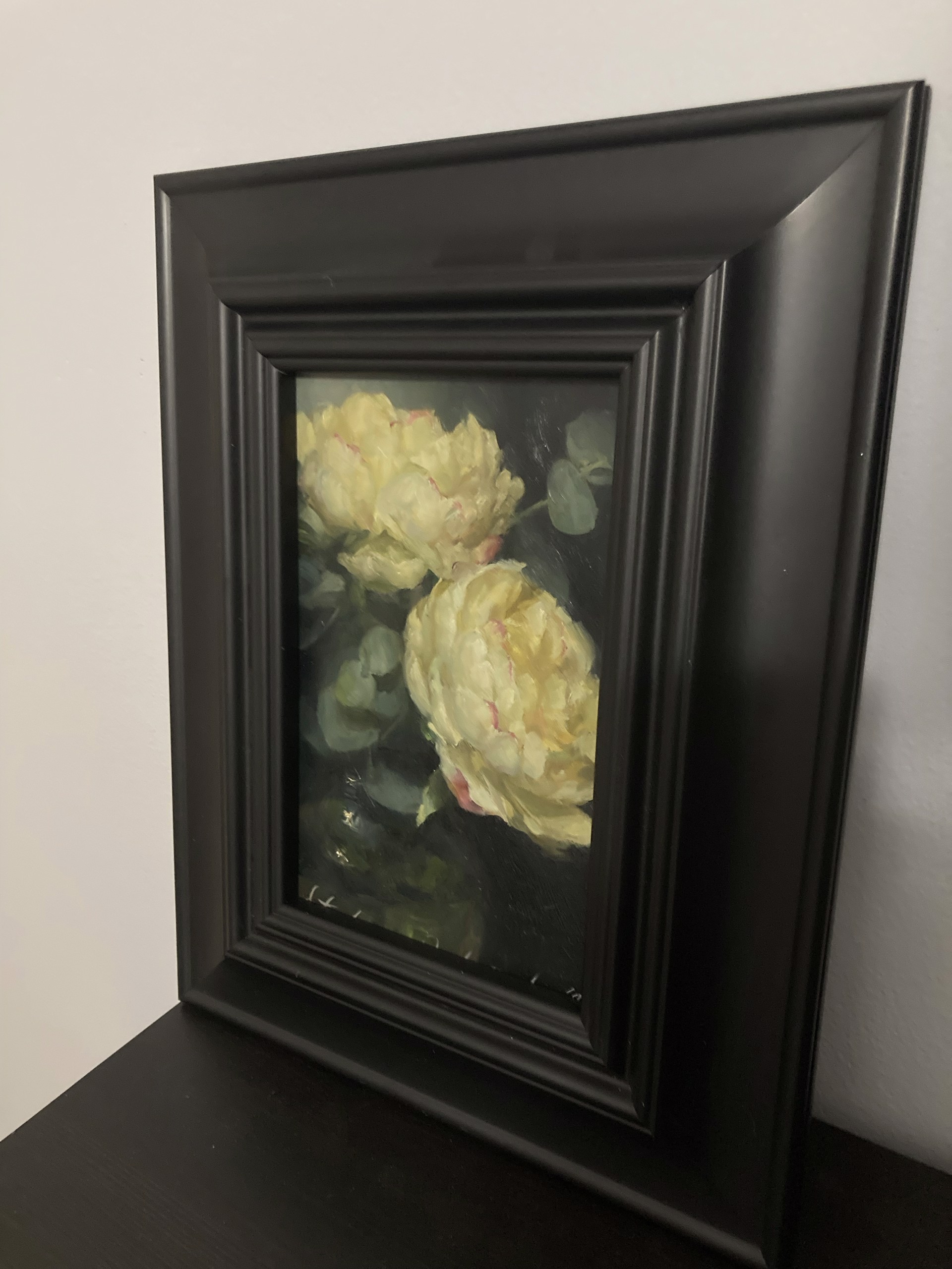 A painting of two yellow roses in a vase on a table.
