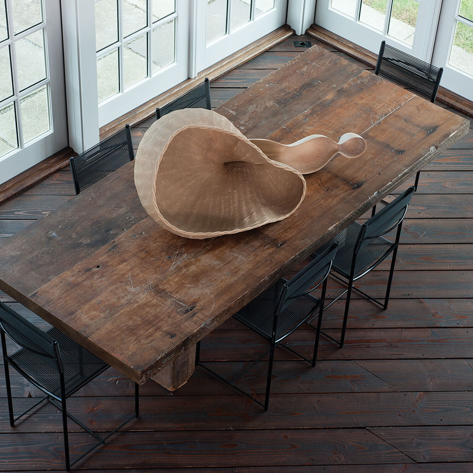 A wooden sculpture resembling a giant spoon resting on slate tiles.