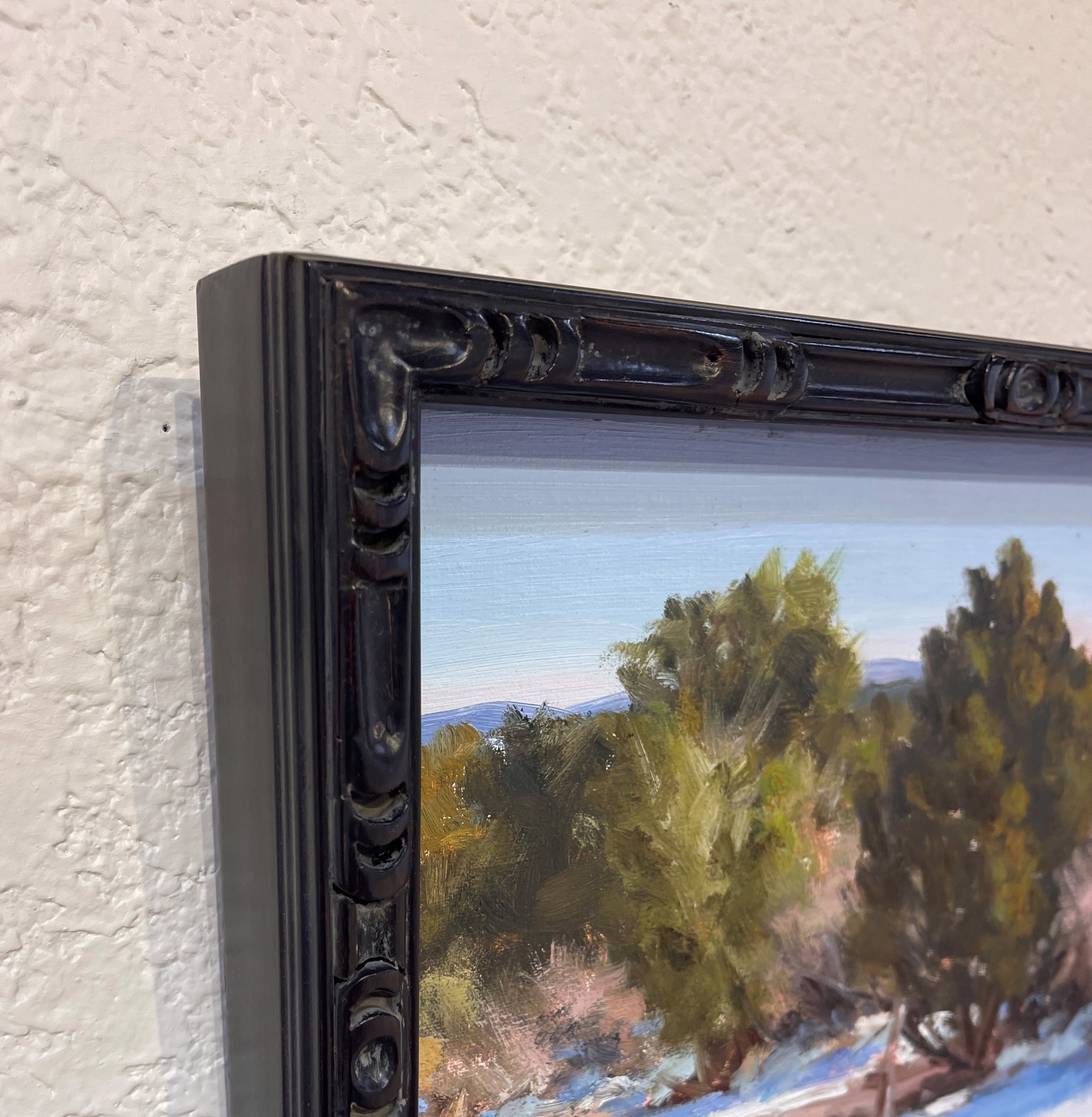 A painting of a snowy landscape with trees in the background.