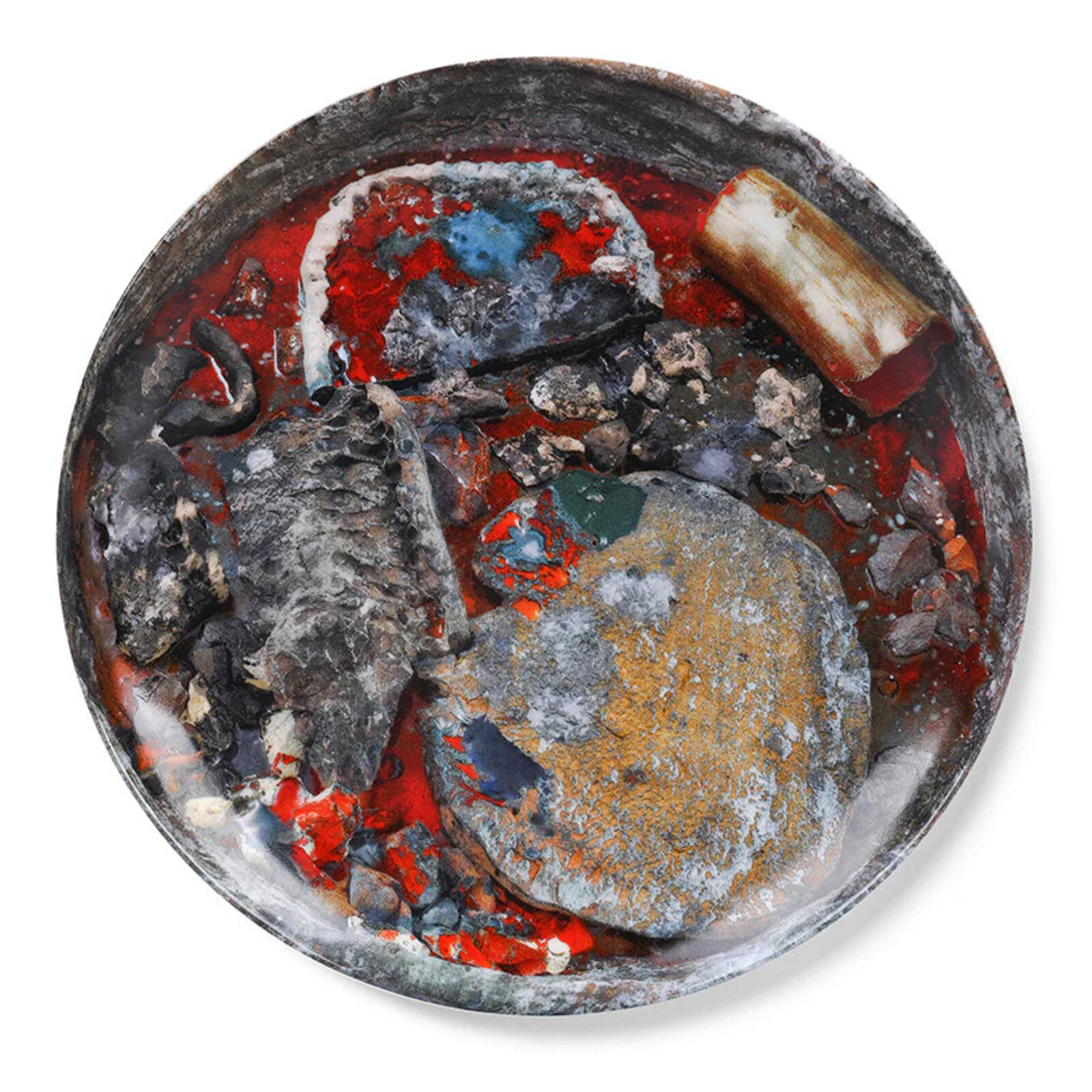 A metal bowl filled with rocks and other items on a white surface.