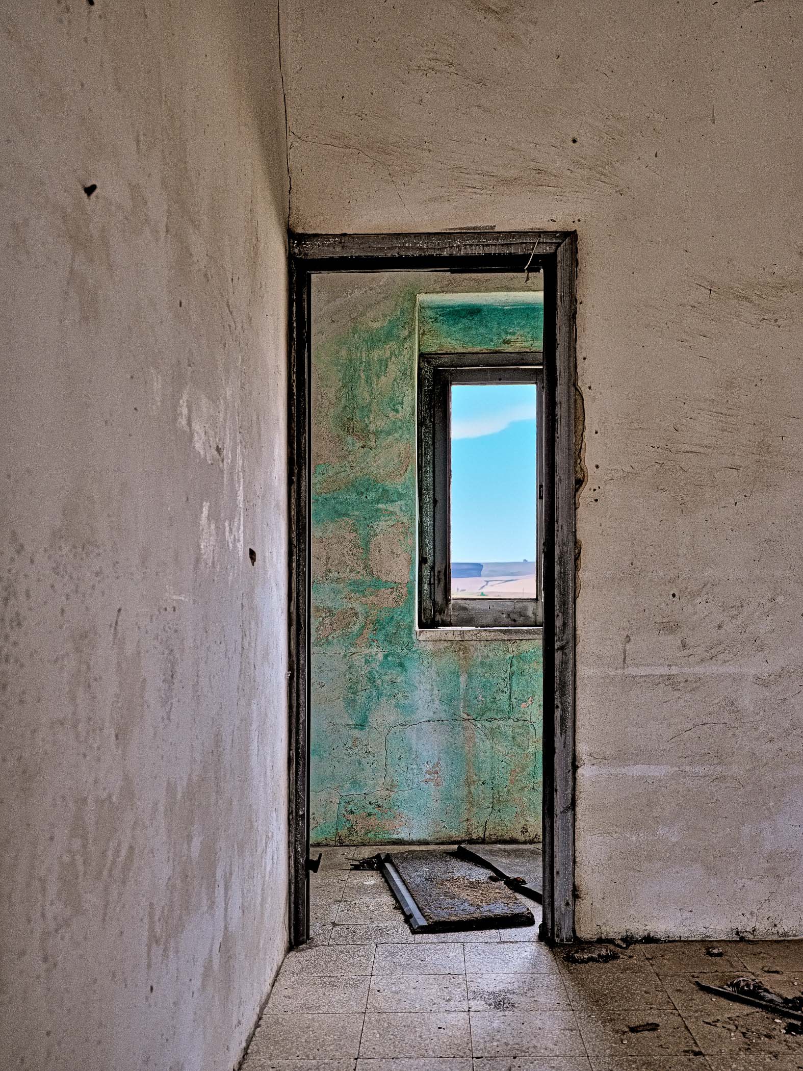 A door in an abandoned building with a window in it.