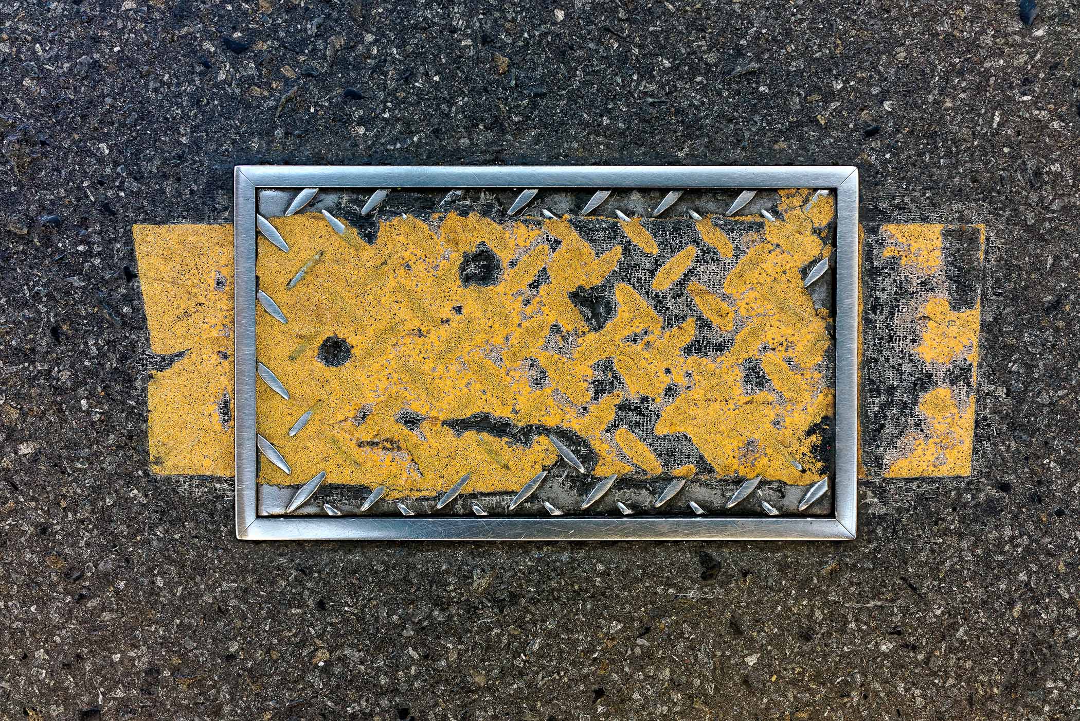 A yellow and black sign on the ground with a metal frame.