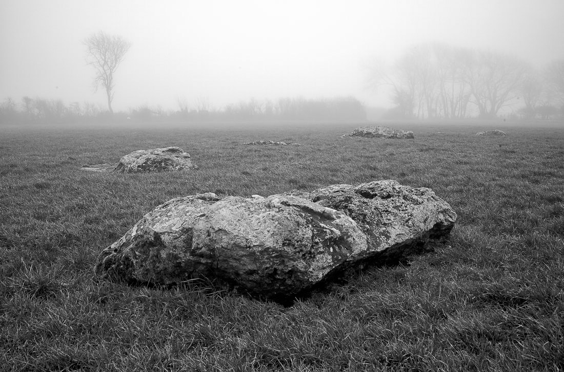A large rock in the middle of a foggy field.