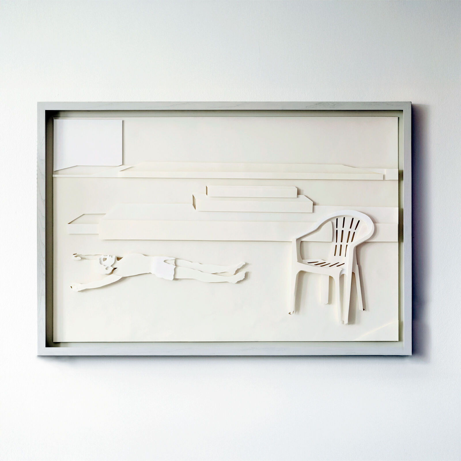 A picture of a white chair and a white table in a shadow box.