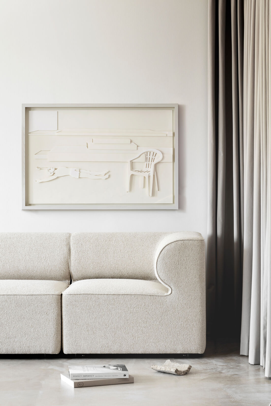 A picture of a white chair and a white table in a shadow box.
