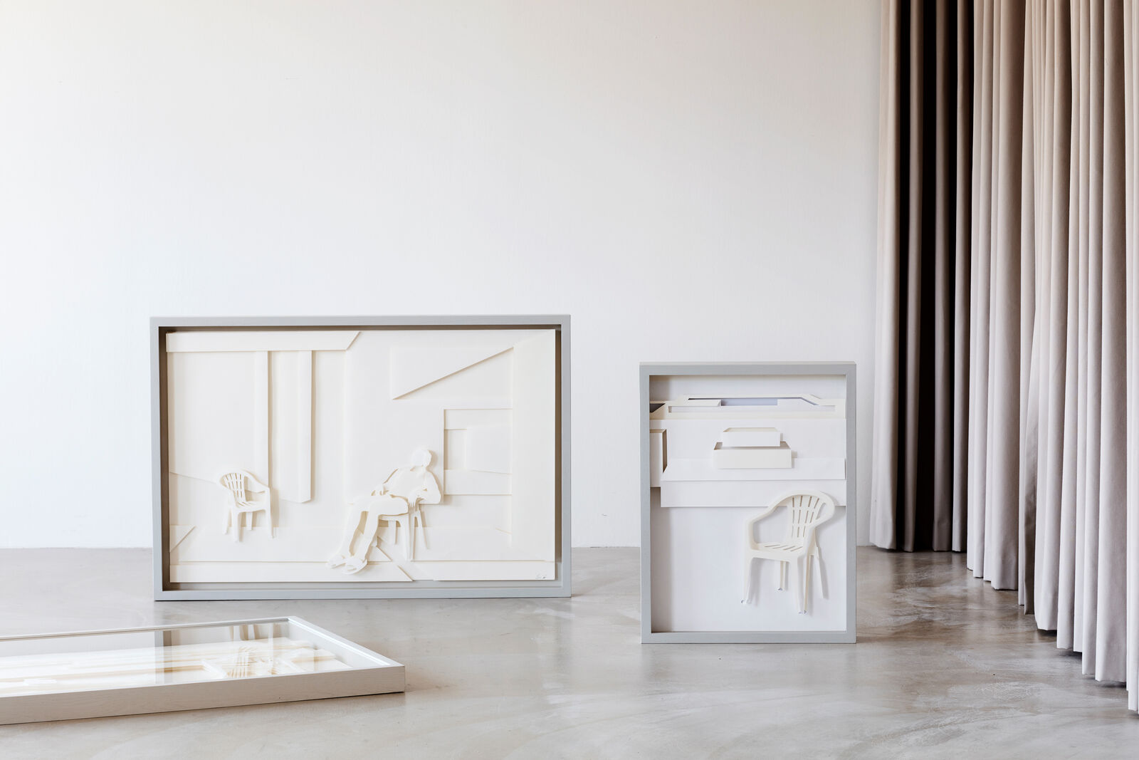 A paper sculpture of a man sitting on a chair in a room.