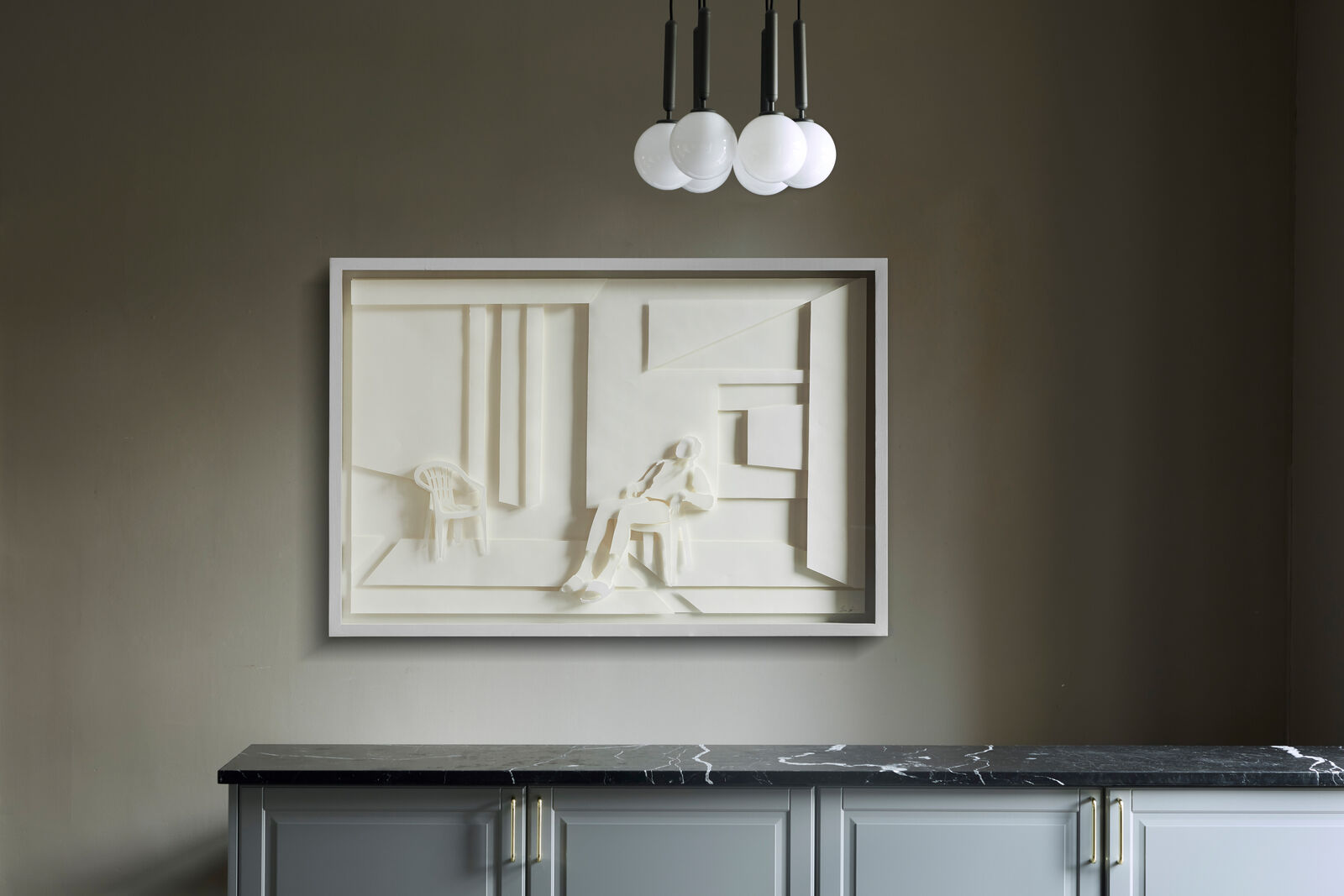A paper sculpture of a man sitting on a chair in a room.