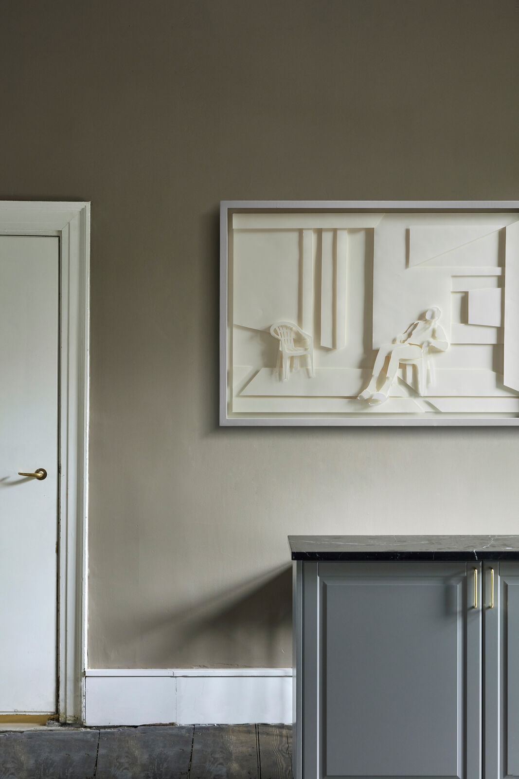 A paper sculpture of a man sitting on a chair in a room.