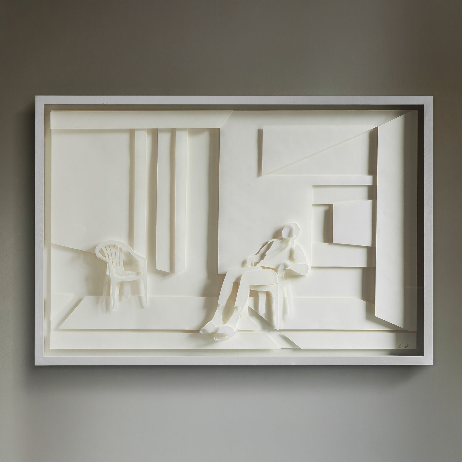 A paper sculpture of a man sitting on a chair in a room.