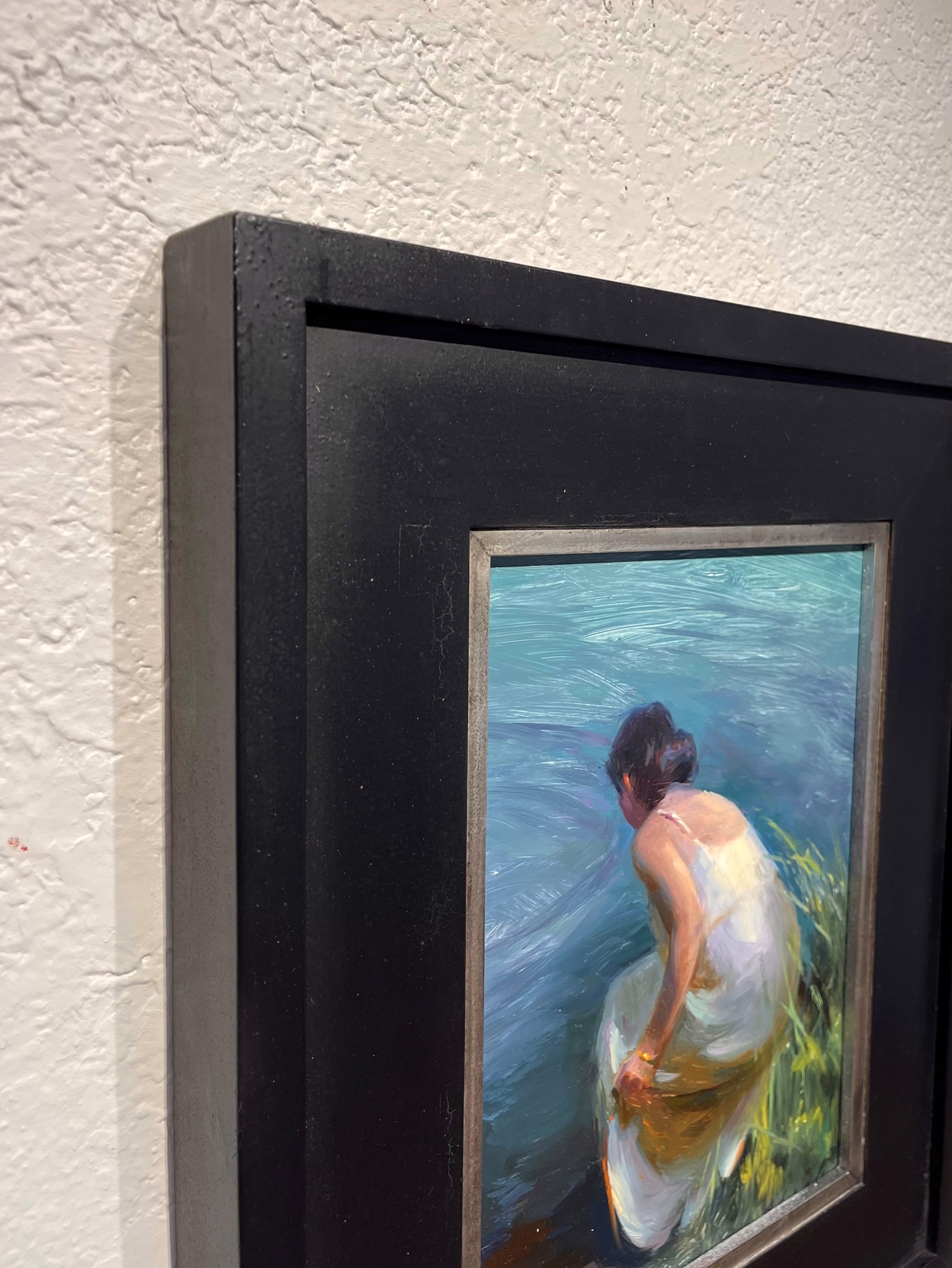 A painting of a woman sitting on the shore of a lake.