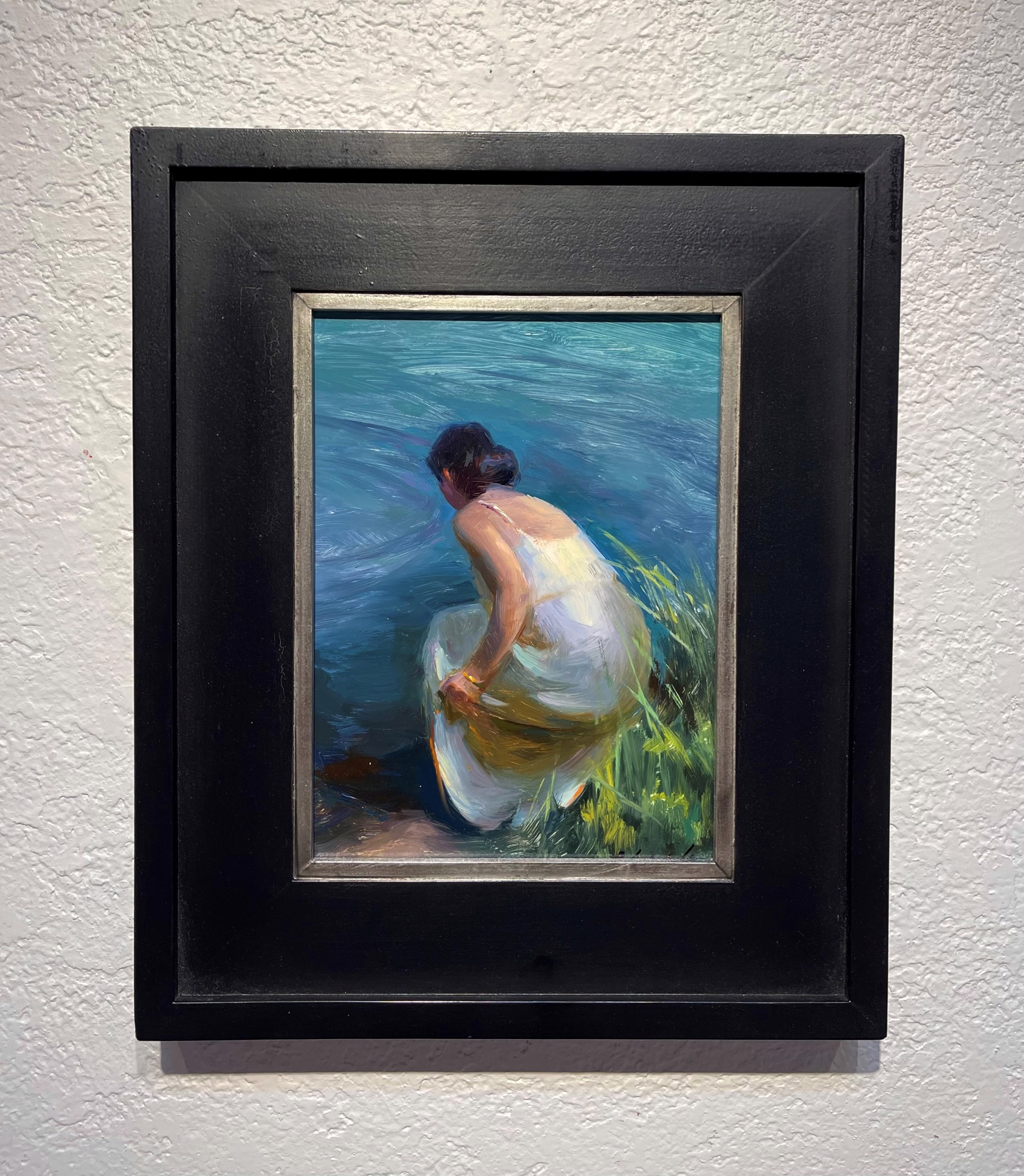 A painting of a woman sitting on the shore of a lake.