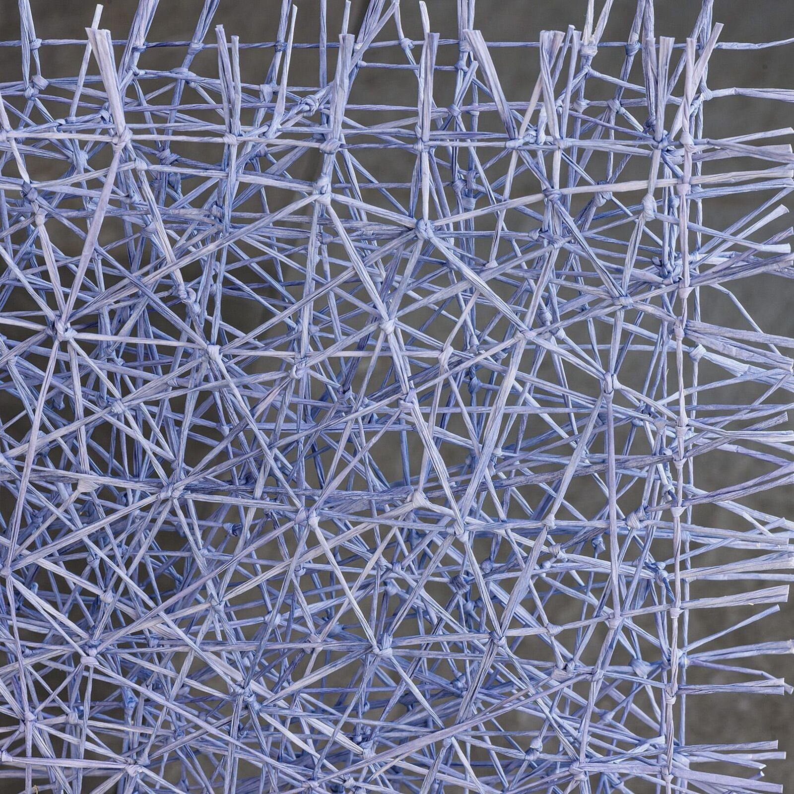 A light blue wire sculpture shaped like a stylized letter 'H' stands on a stone floor.